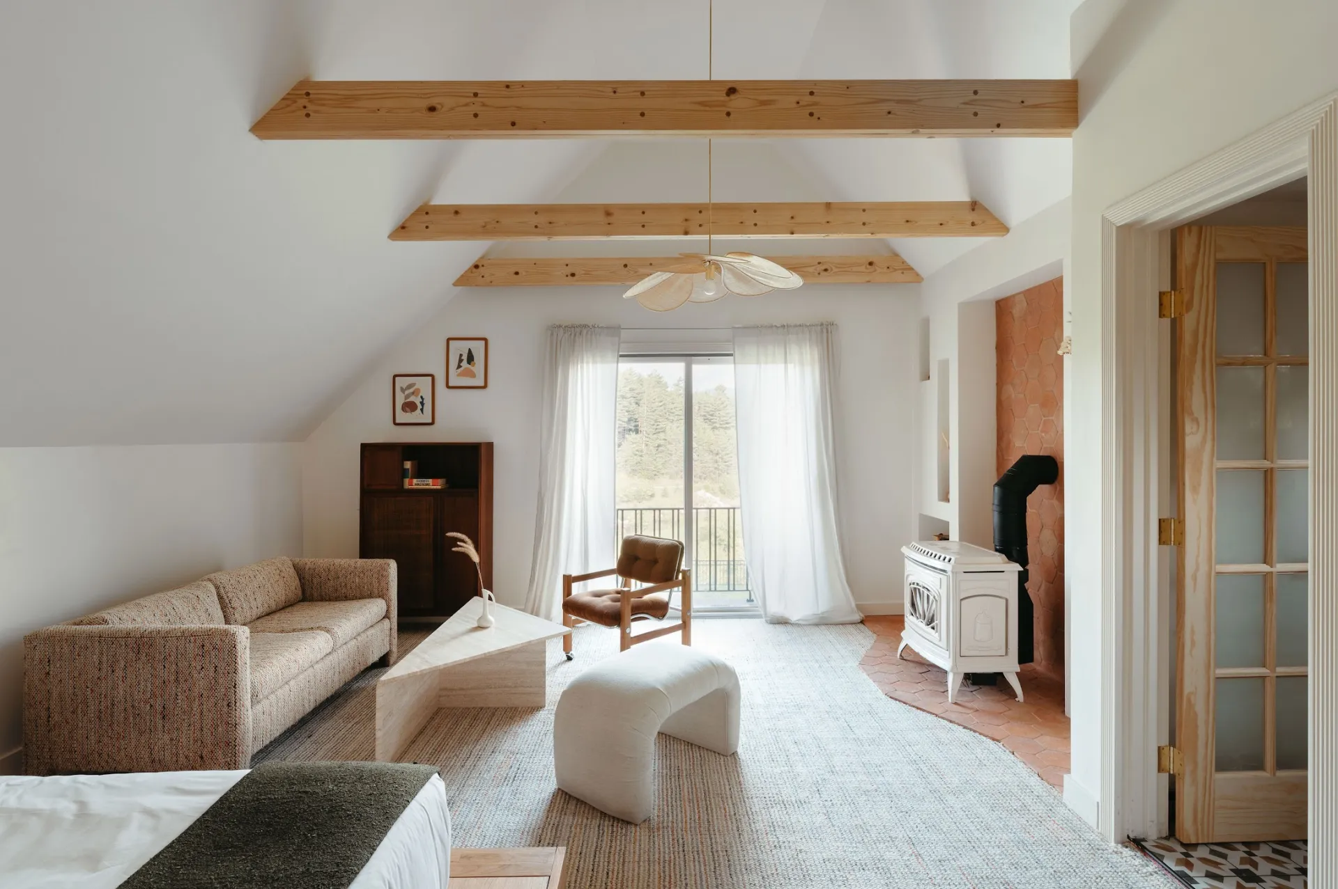 A light and airy living space with couch, balcony and white woodstove at Eastwind Lake Placid