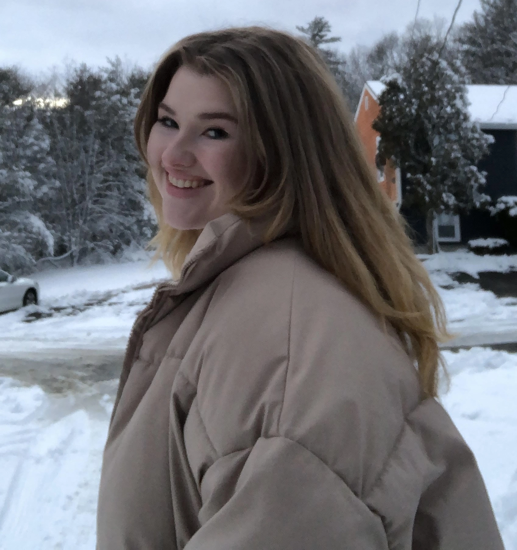 A woman smiles at the camera in a snowy image. 