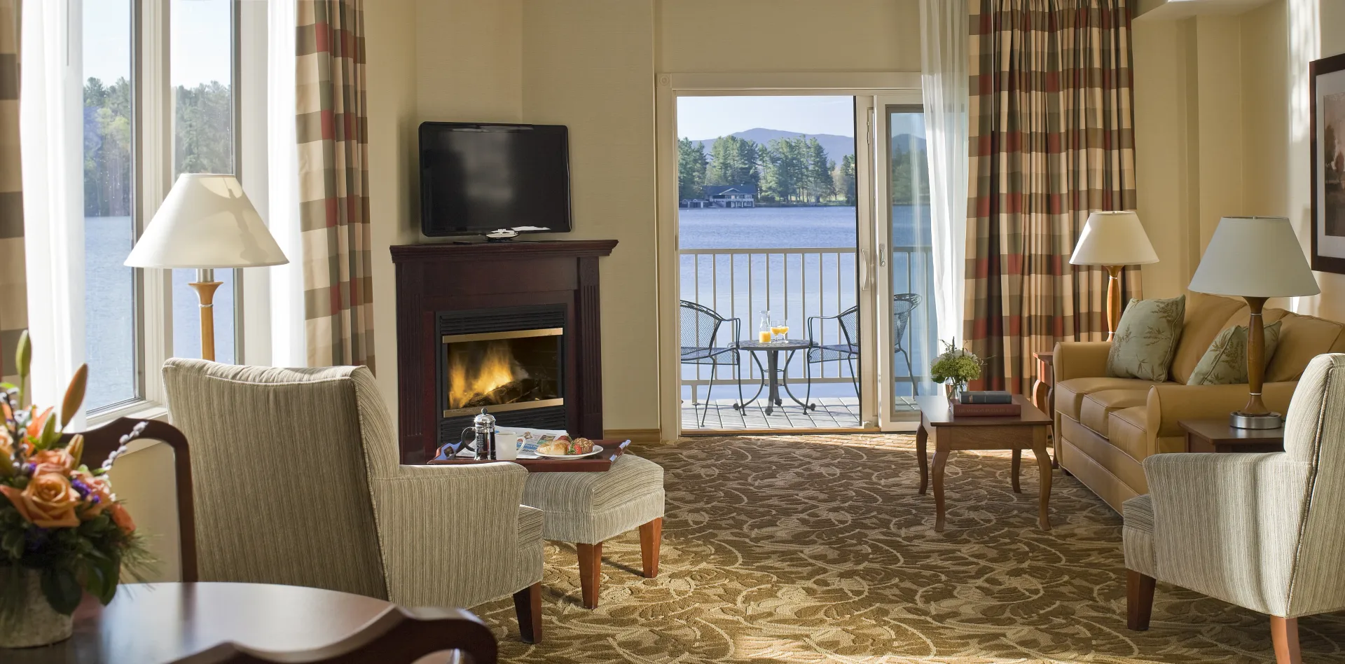 Sitting area with fireplace leading to a balcony with table and chairs through large glass door