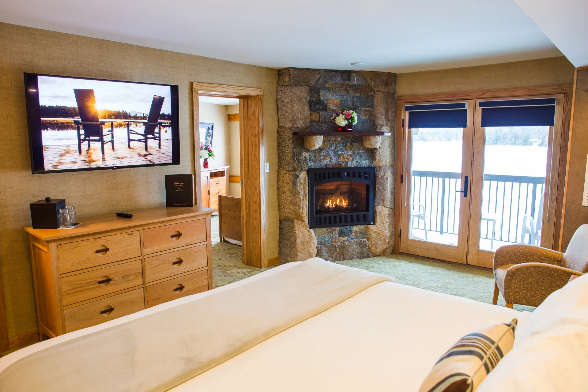 A stone fireplace in the corner of a lush room next to the door to a balcony.
