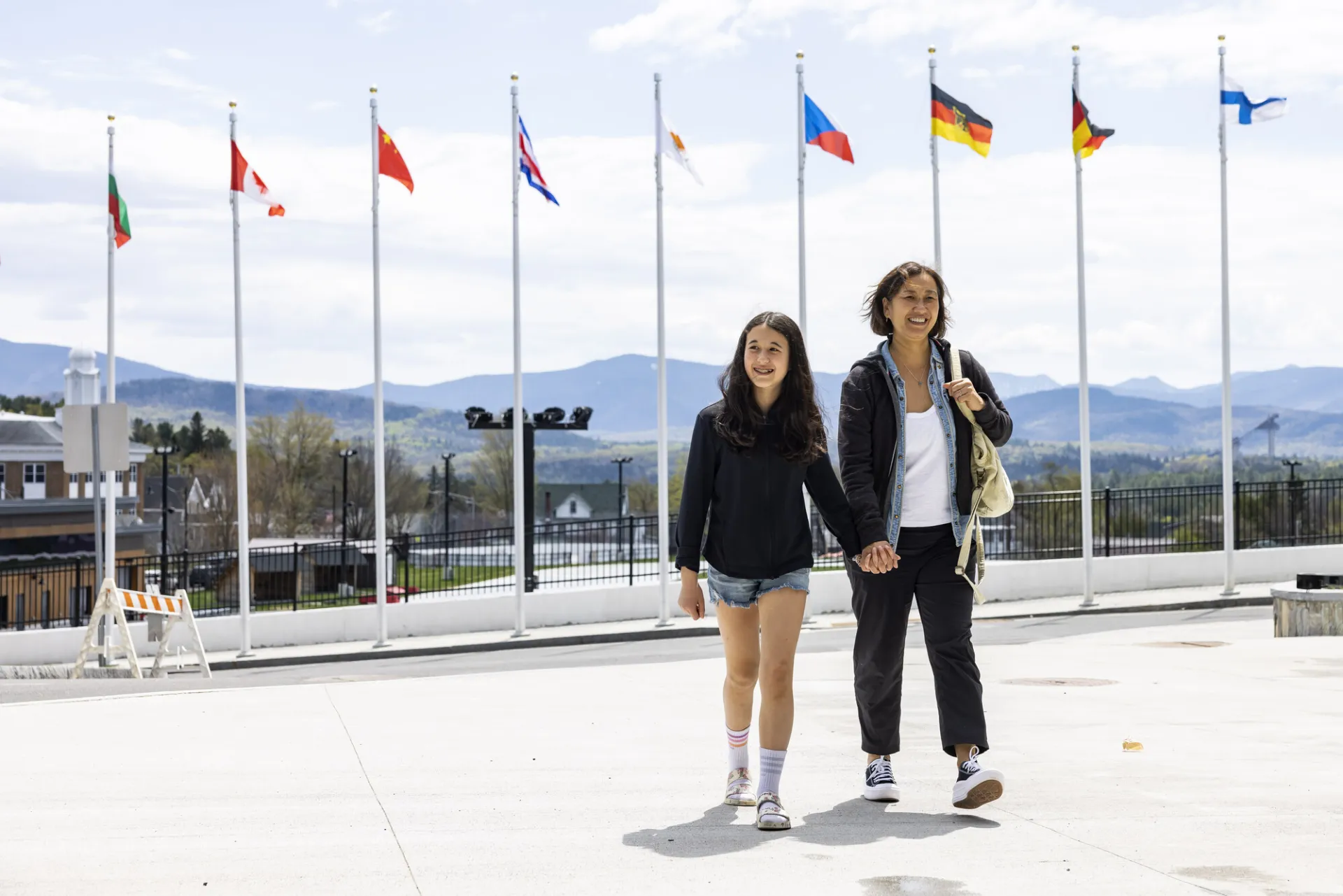 A woman and her daughter walk in front of olympic flags. 