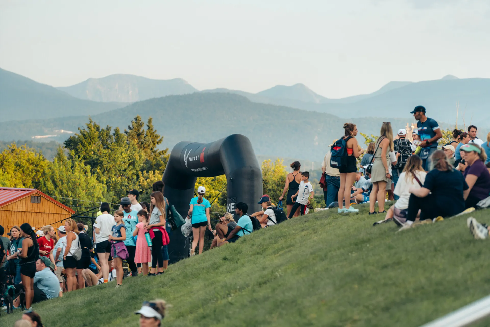Spectators on hill above Ironman finish with mountains in background