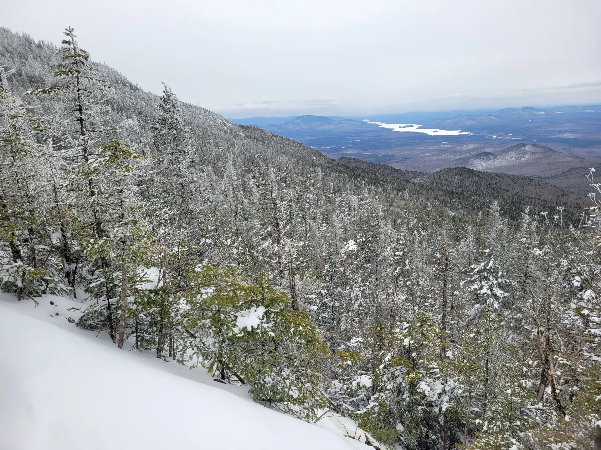 A snowy view down towards a long lake