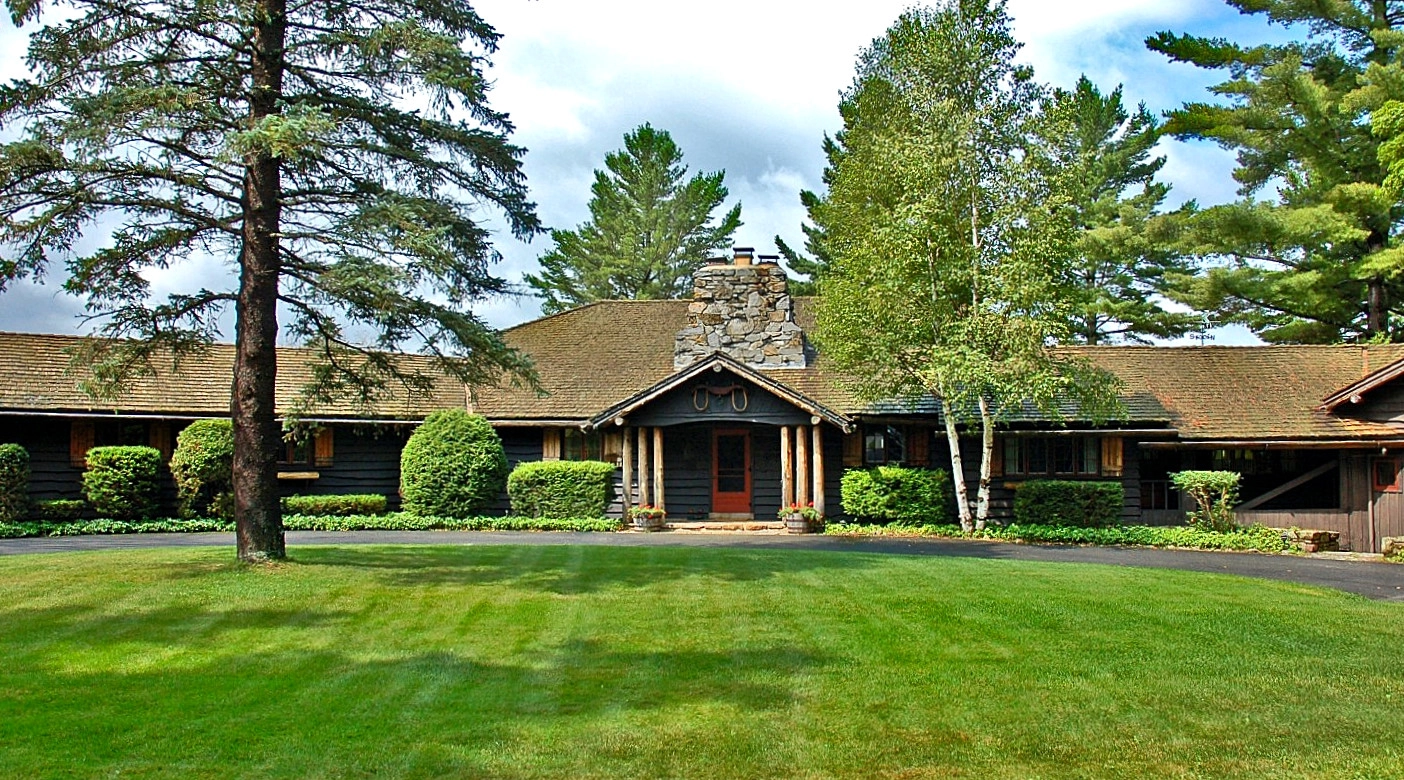 Exterior entrance of the home with the stone fireplace visible.