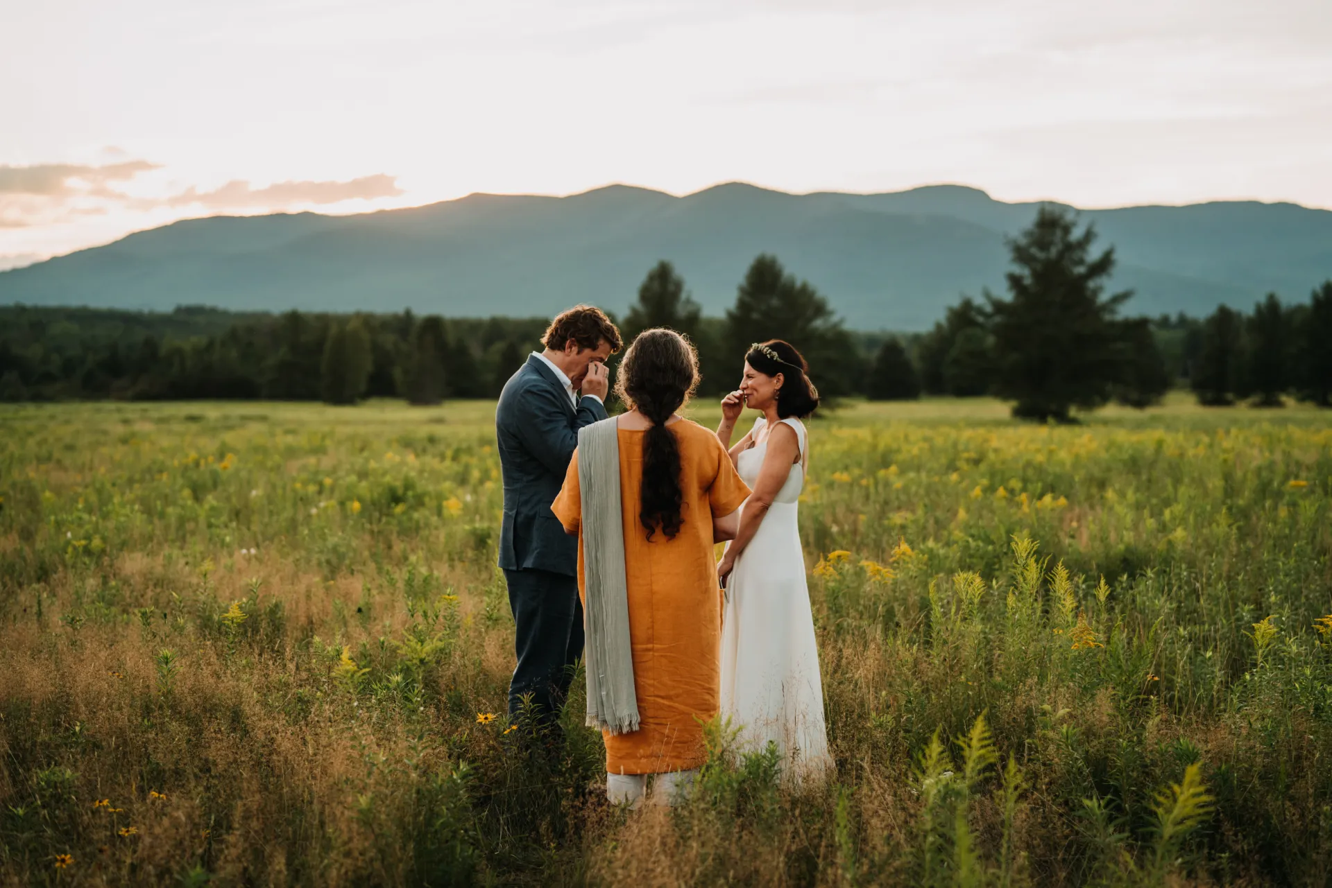 a couple being married in an open field with mountains in the background