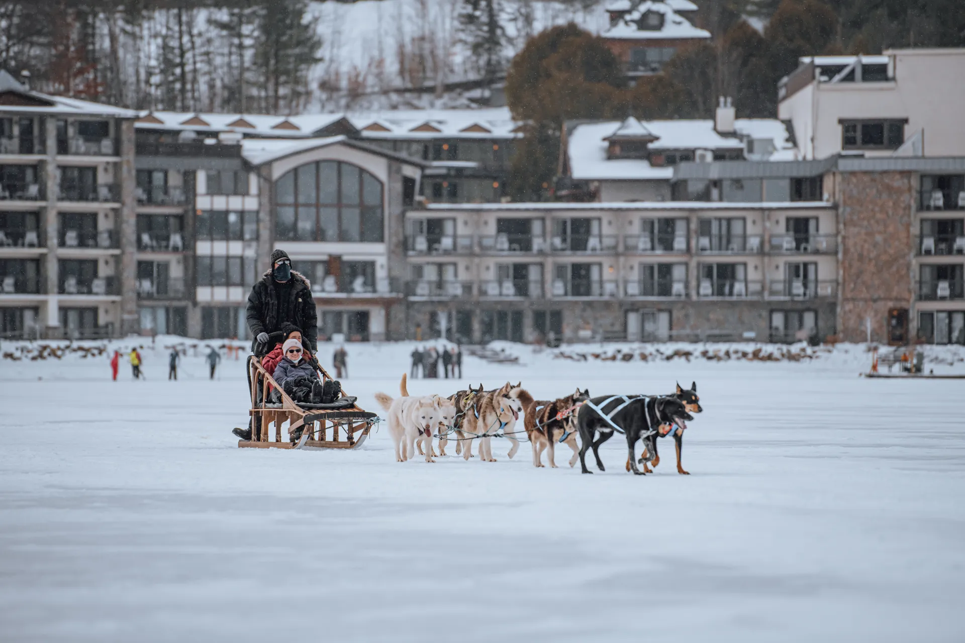 Golden Arrow Lakeside Resort from a frozen Mirror Lake as a team of dog sledders ride by.