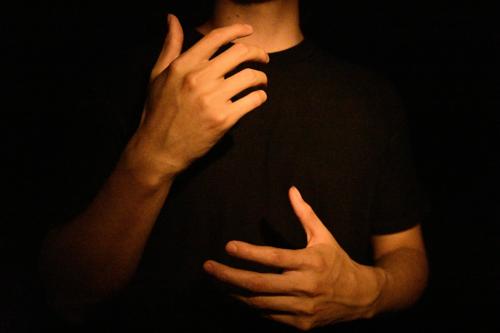 Stock image of person in black shirt signing with their hands with only their hands and forearms visible.