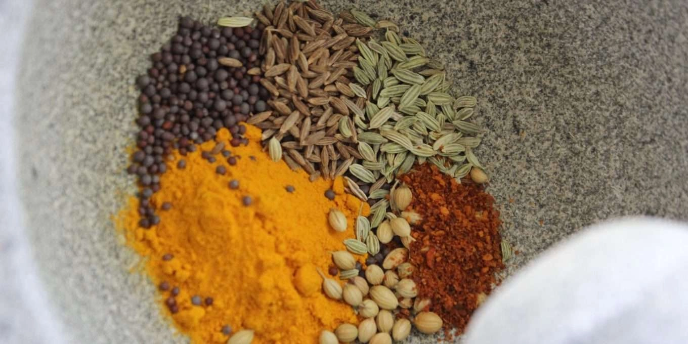 Herbs and spices of various colors in a bowl