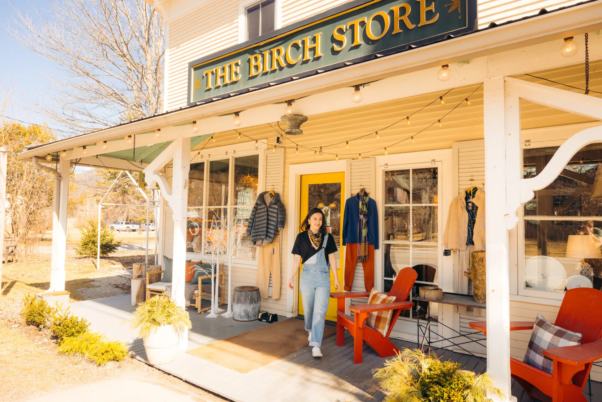A woman in overalls walks out of a country store.