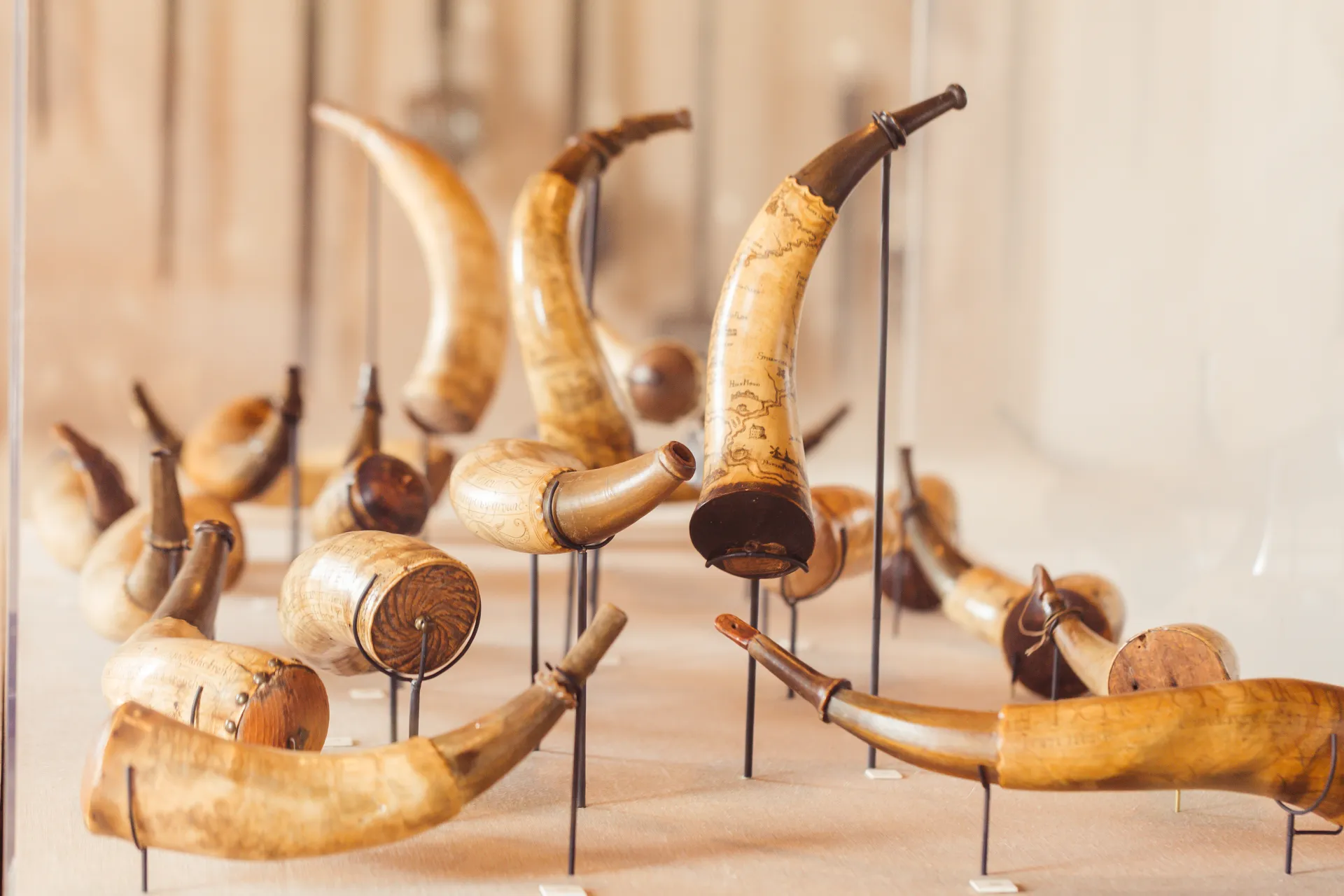 A collection of powder horns, some decorated with maps and adorned with metal dispensing tips.