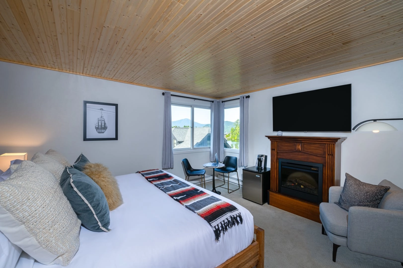 White linens on the large bed facing the dual windows facing the mountains over the lake.