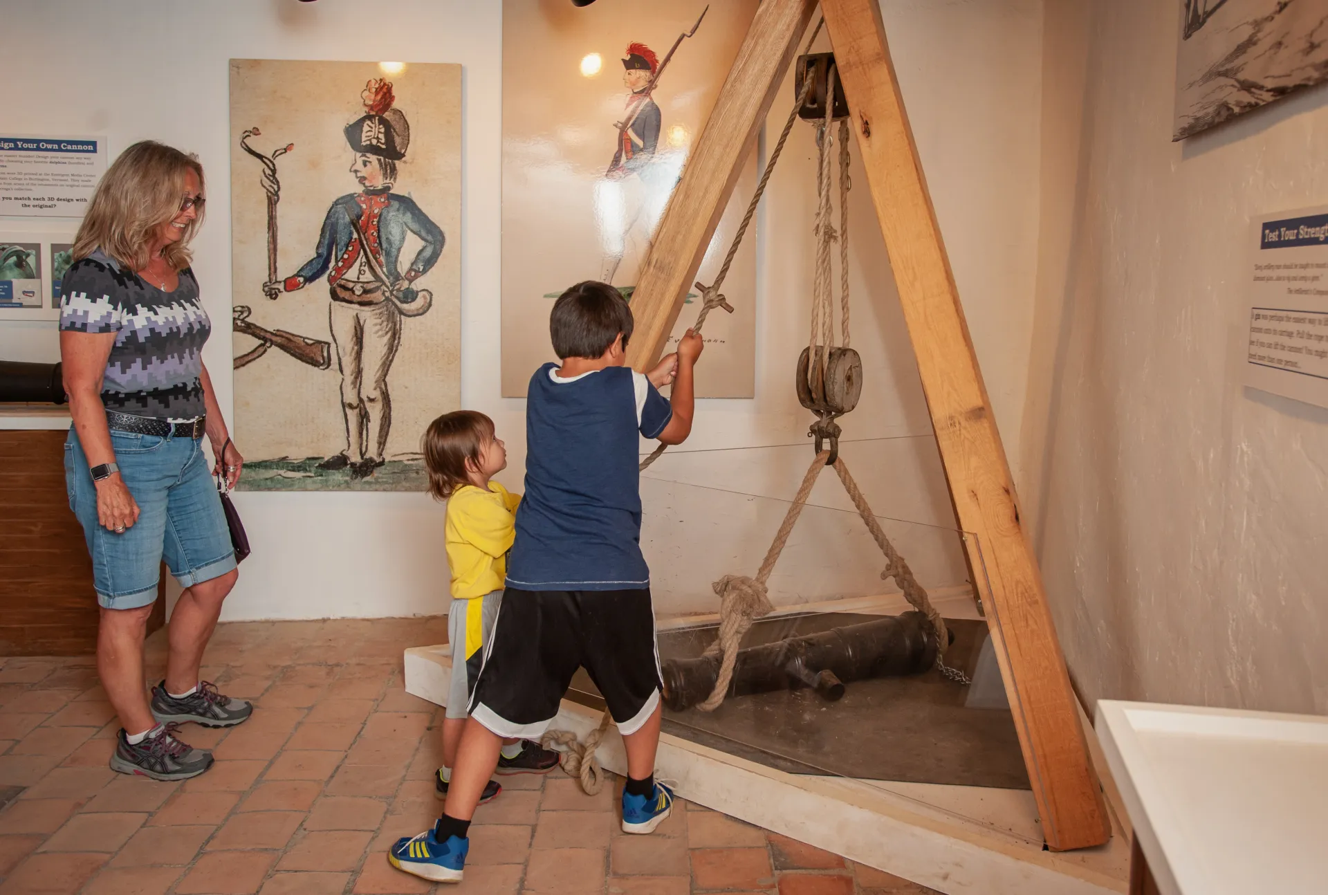 Children try to hoist a cannon with traditional rope and wooden pulleys