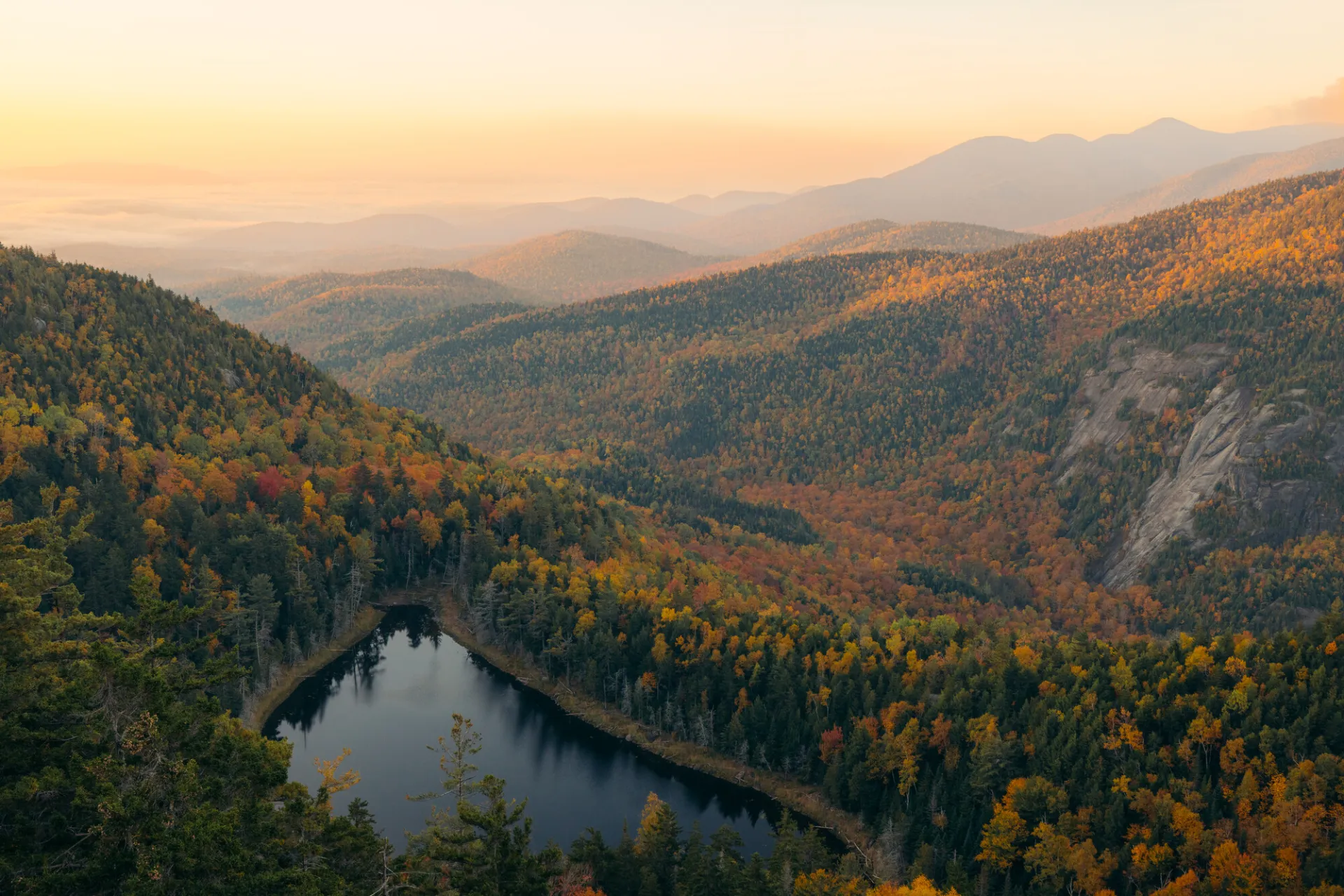 A mountain range with a lake in front of it in fall.