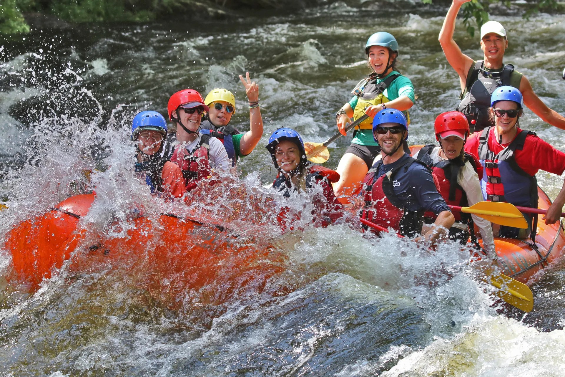 A group of rafters smile and wave at camera
