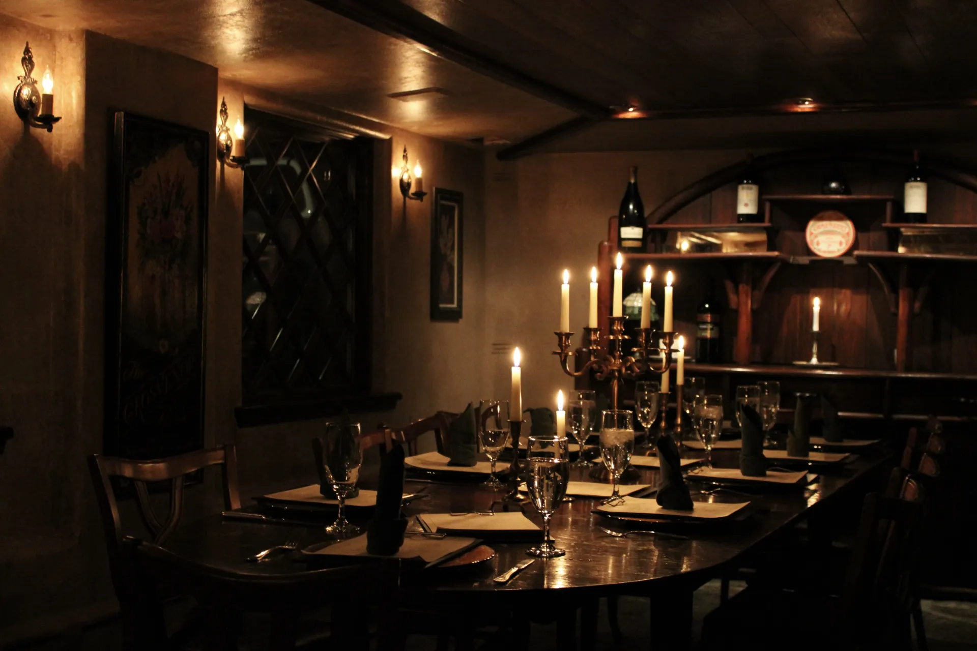 Warm and dark dining space with candles and electric candle sconces.