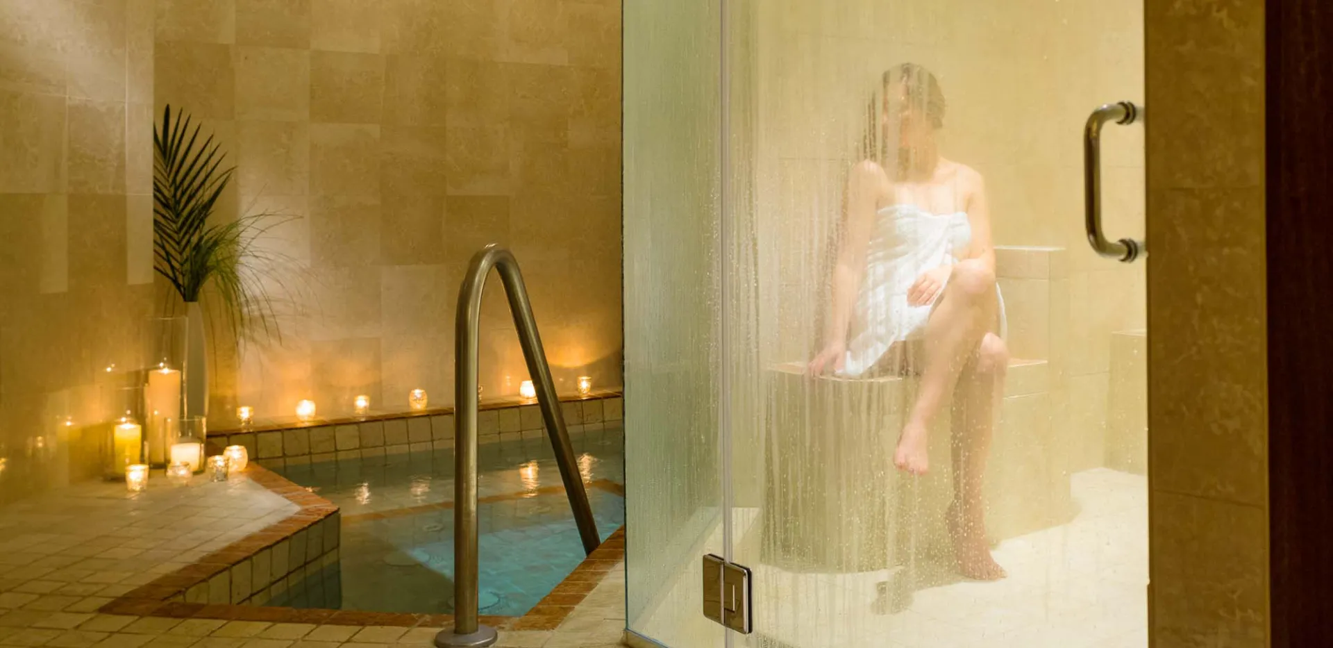 A woman sits wrapped in a lush towel while basking in the rejuvenating steam room.