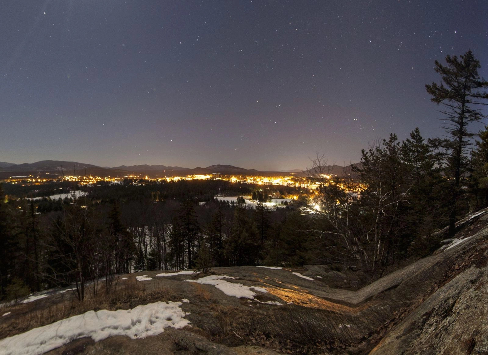Night view of Lake Placid Village from Cobble Hill, with the High Peaks in the background on a starry-starry night