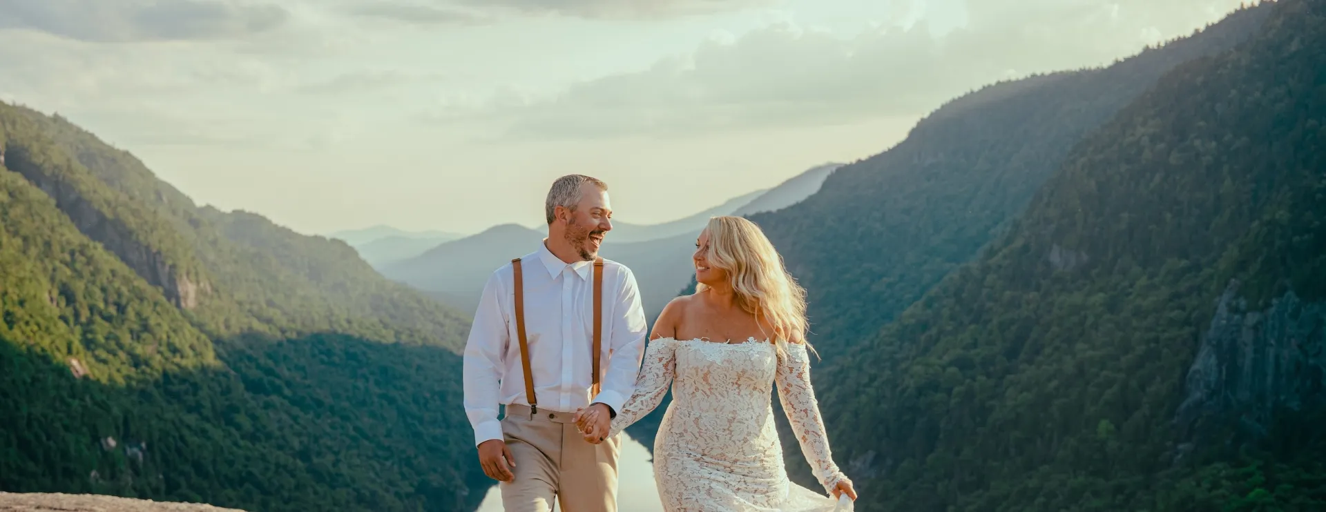 Smiling bride and groom with the valley and mountains surrounding them in the background