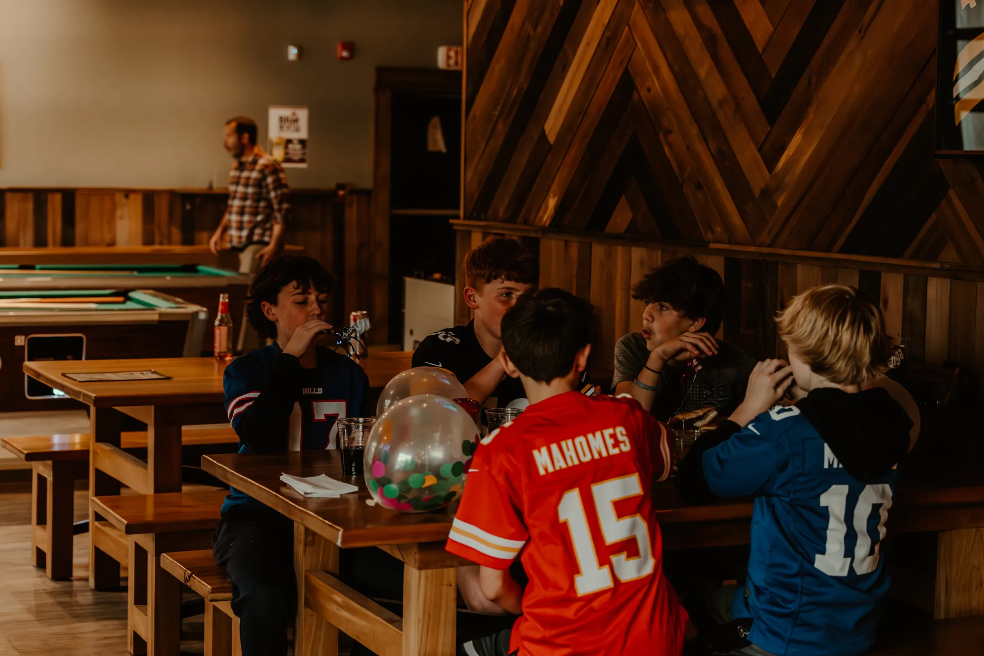 A table full of young boys celebrate in their jerseys.