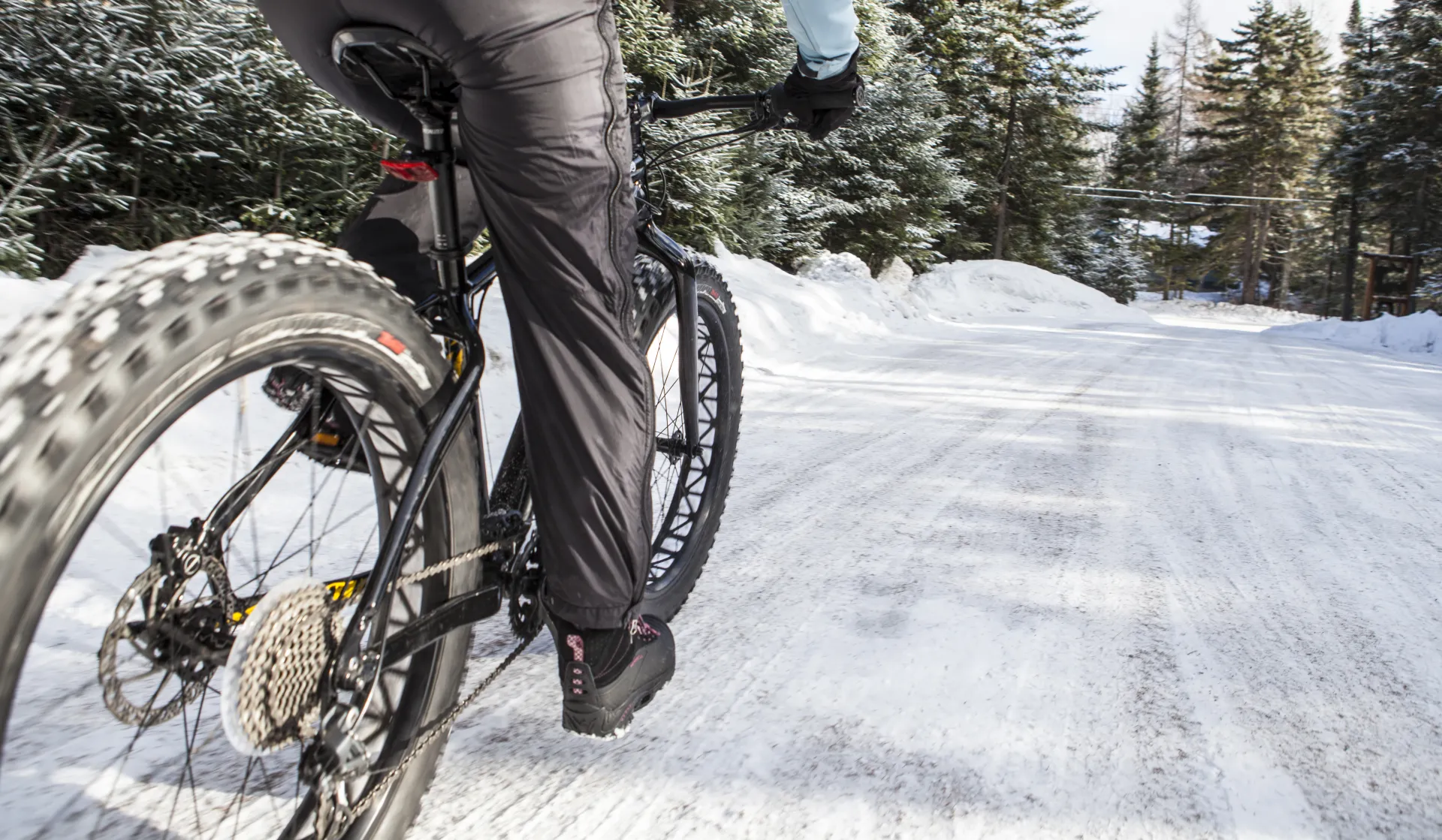 A person rides a fat tire bike down a snowy road