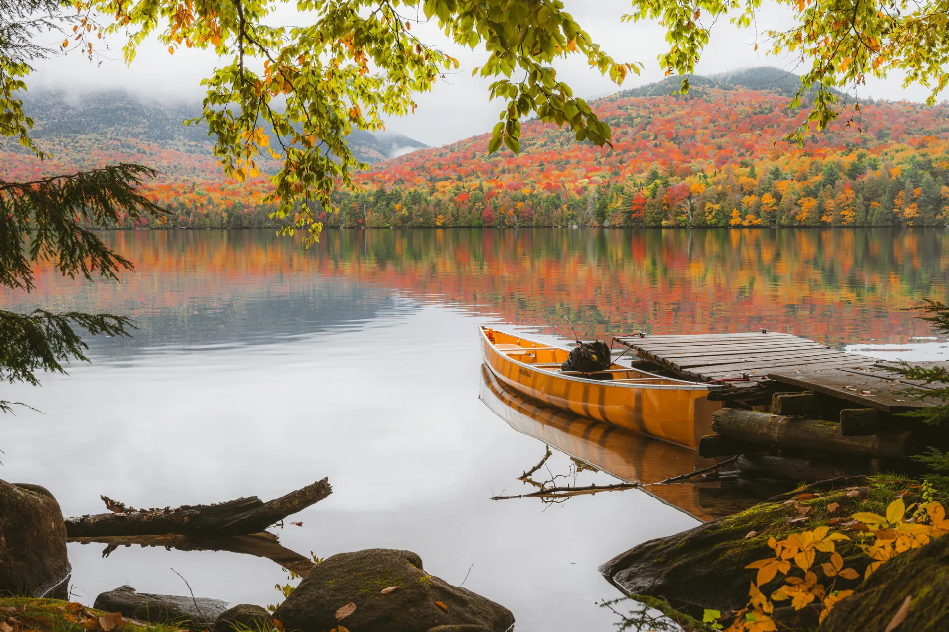 A canoe on a lake with fall scenery.