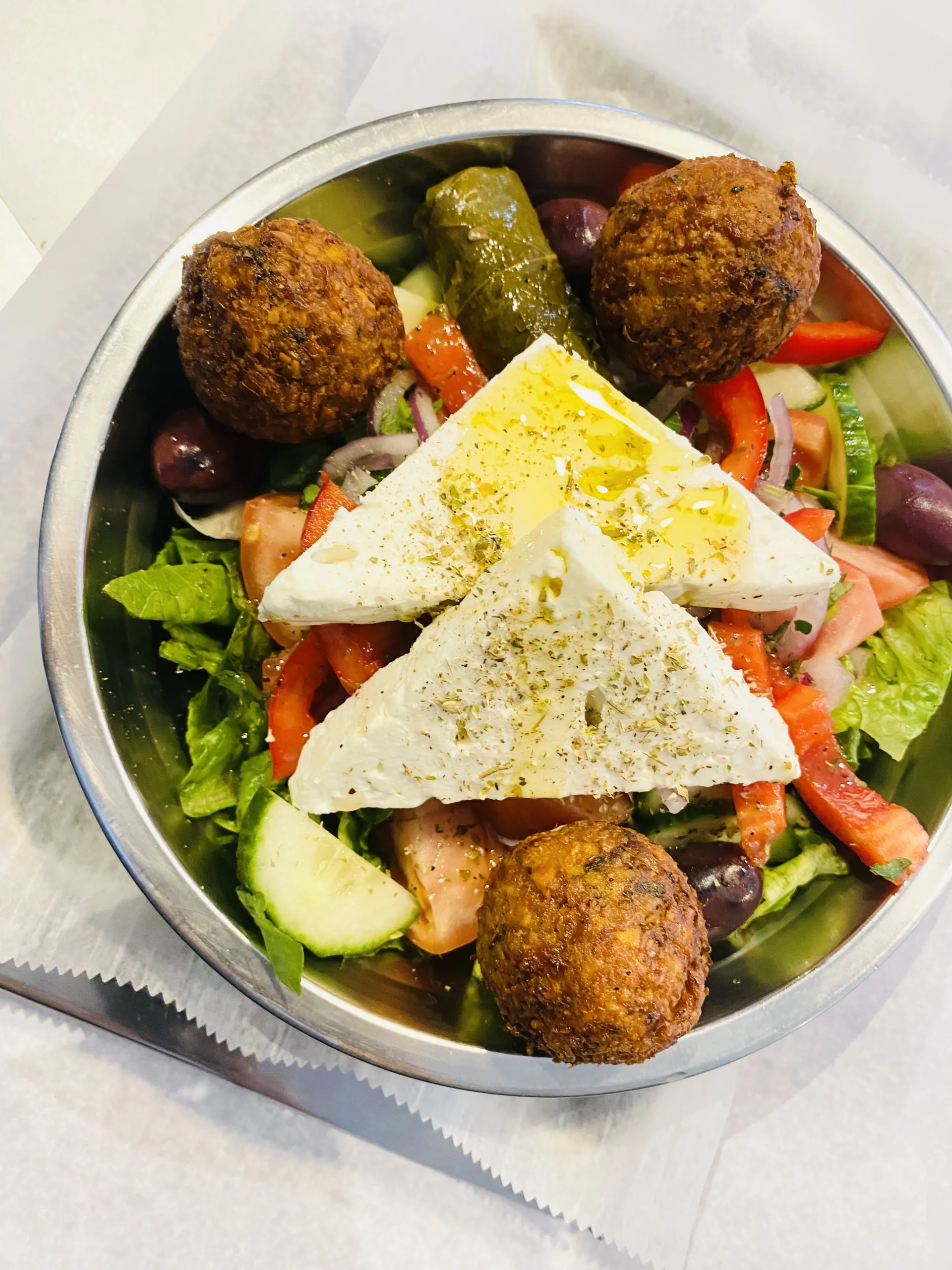 Greek salad with Lettuce, Cucumber, Tomato, Red Onion, Grape Leaves, Red Peppers, Olives, and Feta Cheese, tossed with House Greek Dressing and added Falafel.