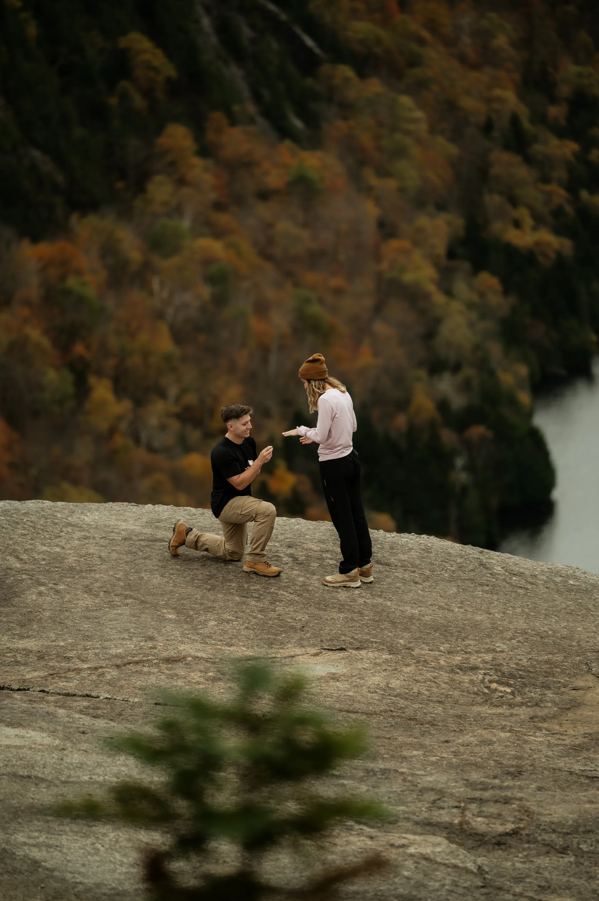 Mountain top engagement with a man on one knee overlooking a lake