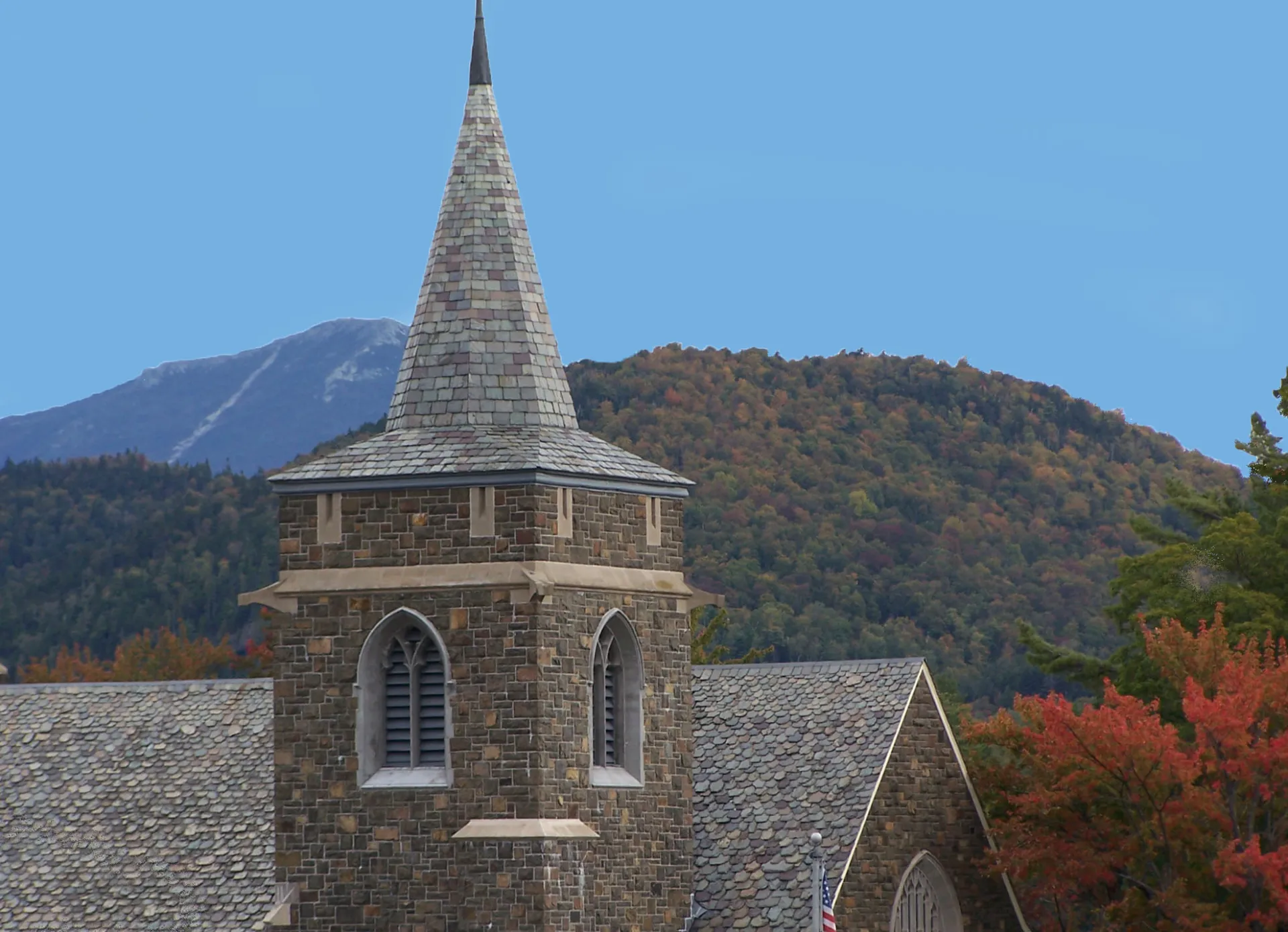 A church steeple among fall foliage. 