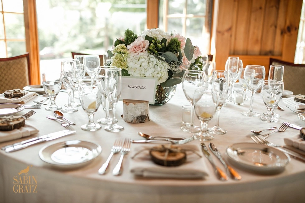 A table setting with white linens and custom High Peak themed table marker "Haystack"