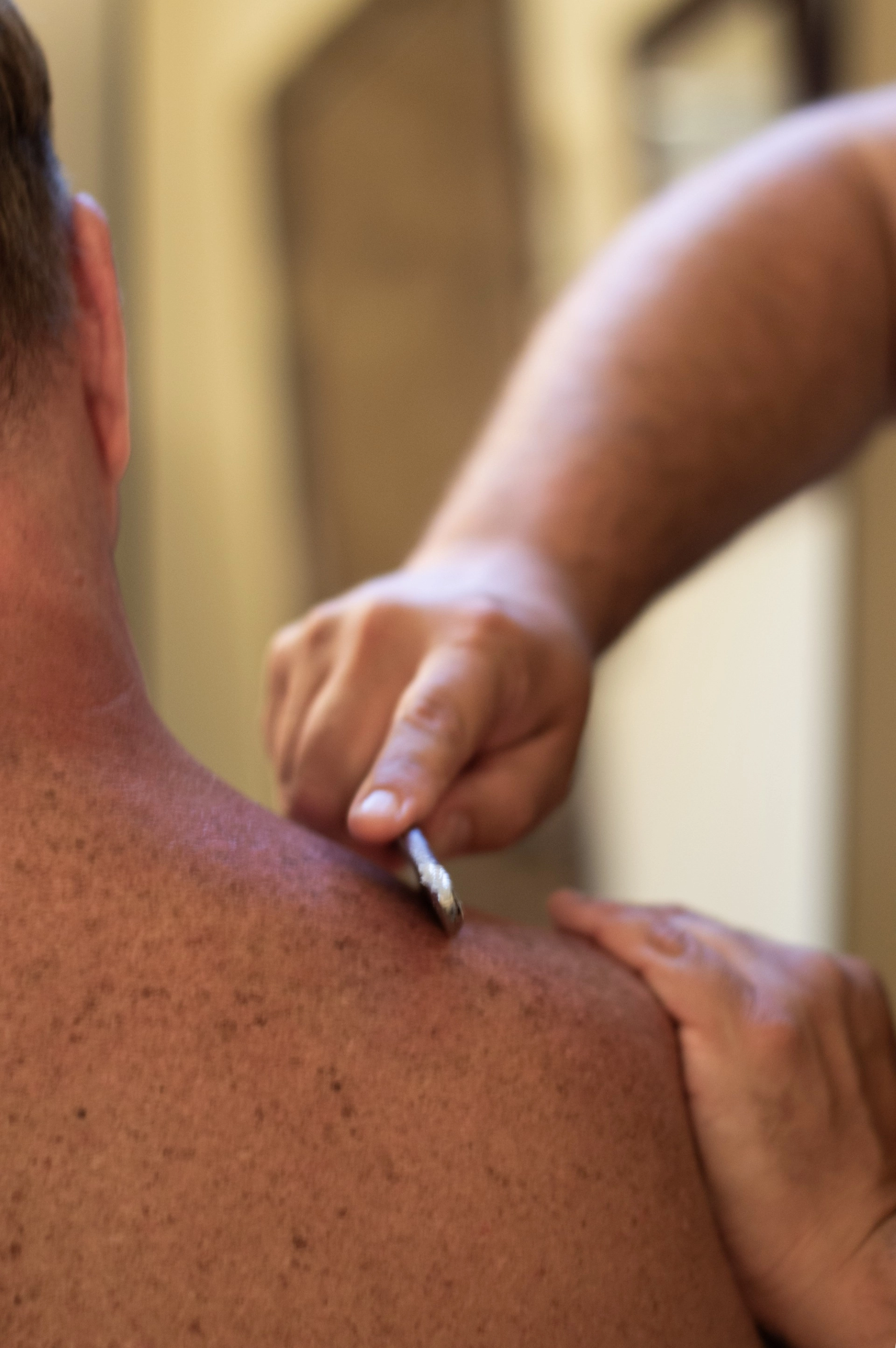 A massage therapist uses a metal tool on a shoulder iastem massage at Healing Elements.