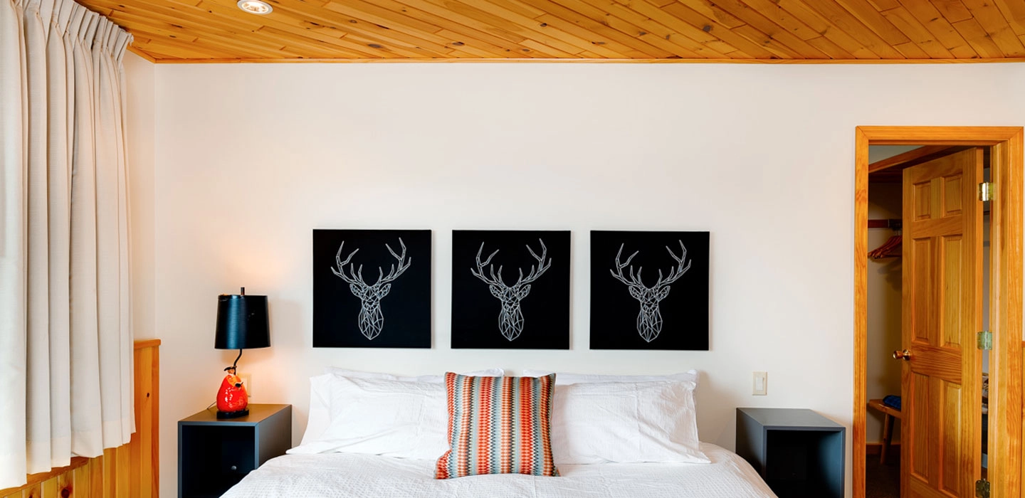 Artwork of a stag above the headboard of a bed.