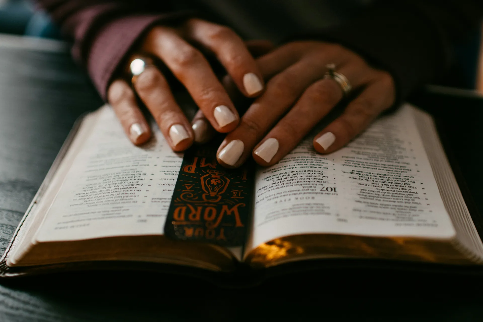 woman's hands on open bible with bookmark