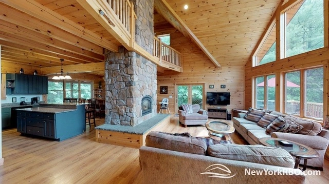 A spacious living room with central fireplace and large couches by the big windows.