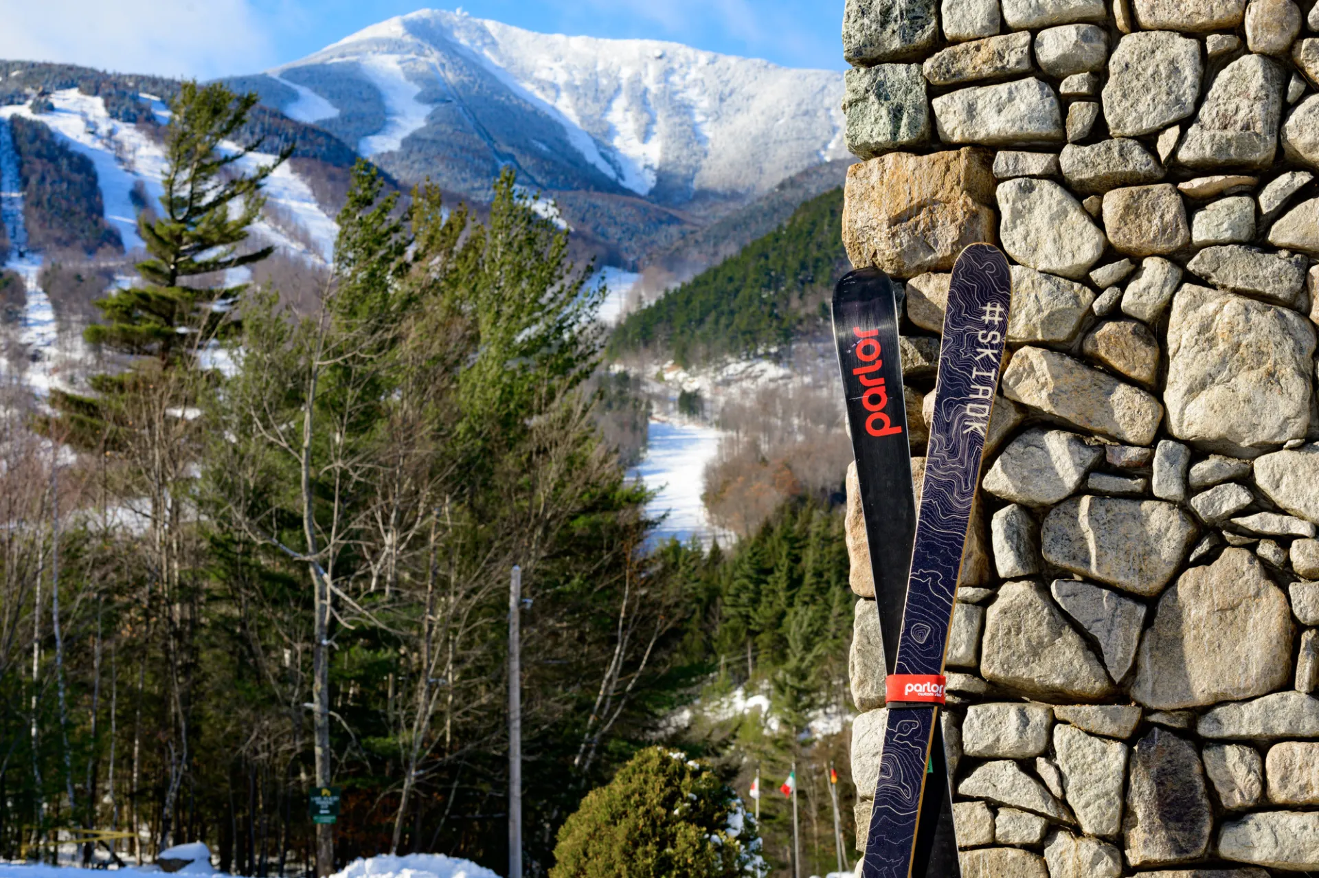 Skis propped against stone wall with Whiteface trails visible in background