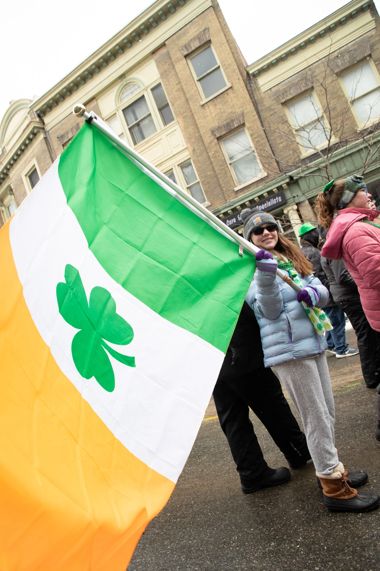 young girl holding irish flag with shamrock at center 
