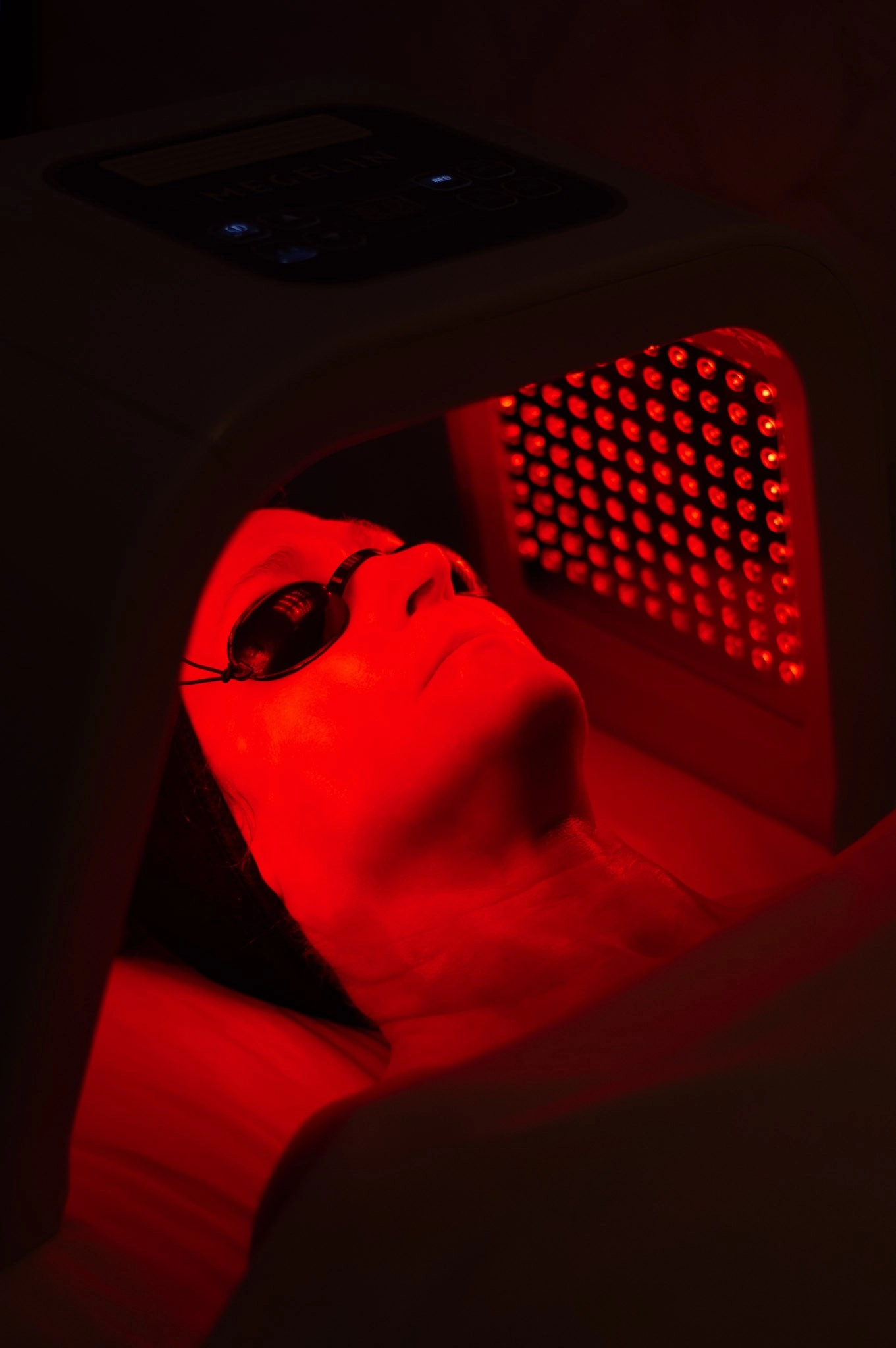 A person receiving a facial wearing eye protection for the red light treatment at Healing Elements.