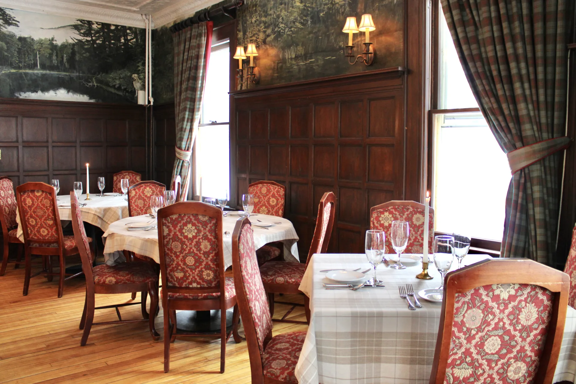 Dining room with light table clothes and dark paneled walls.
