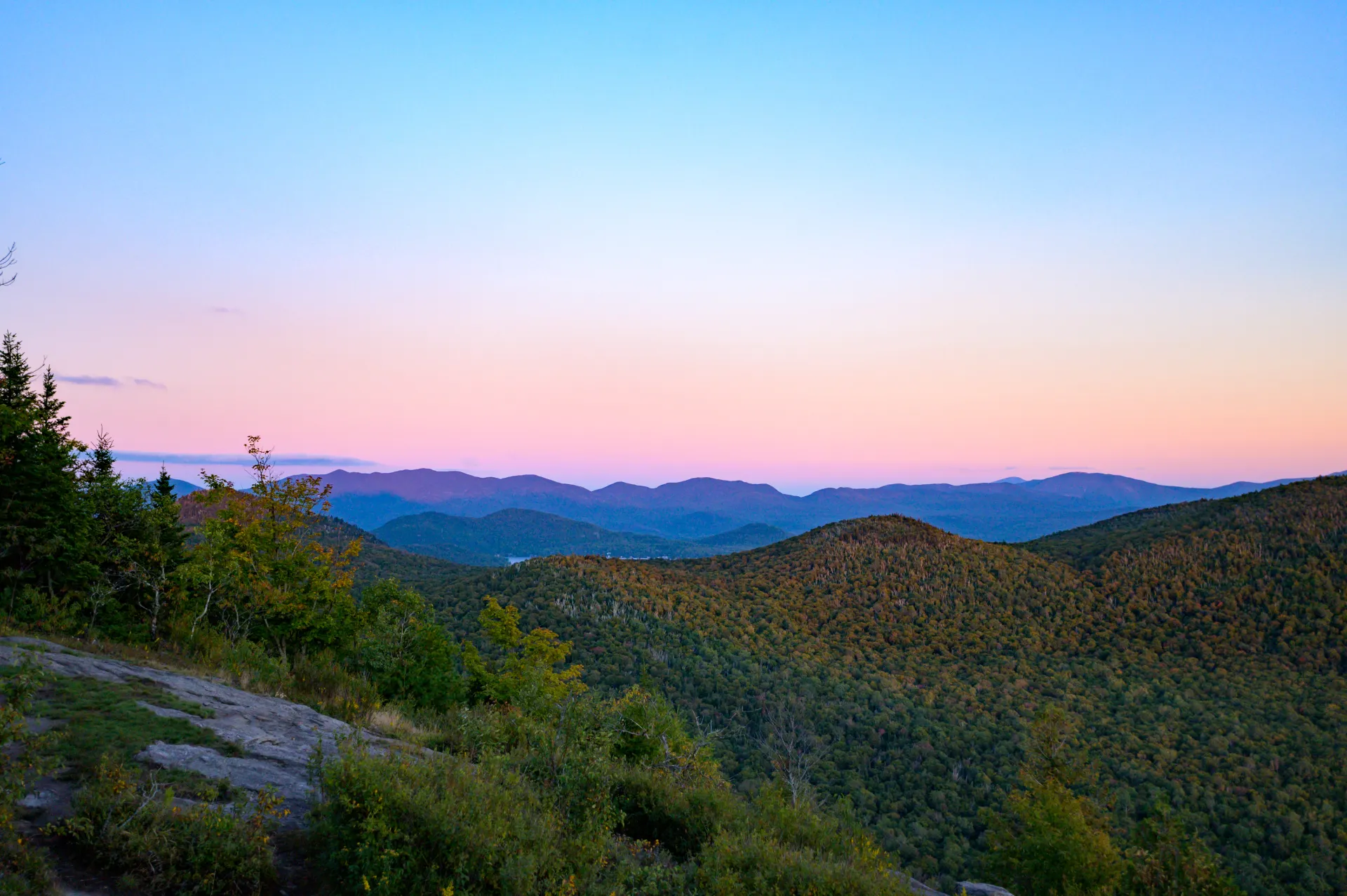 View from the summit of Haystack Mountain Mountain as the sun sets behind the silhouette of the Adirondack Mountains