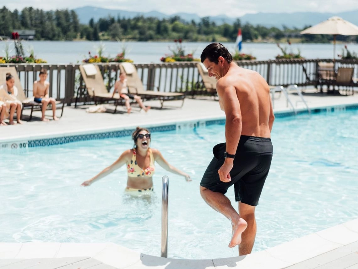 A happy couple plays in the pool overlooking Mirror Lake