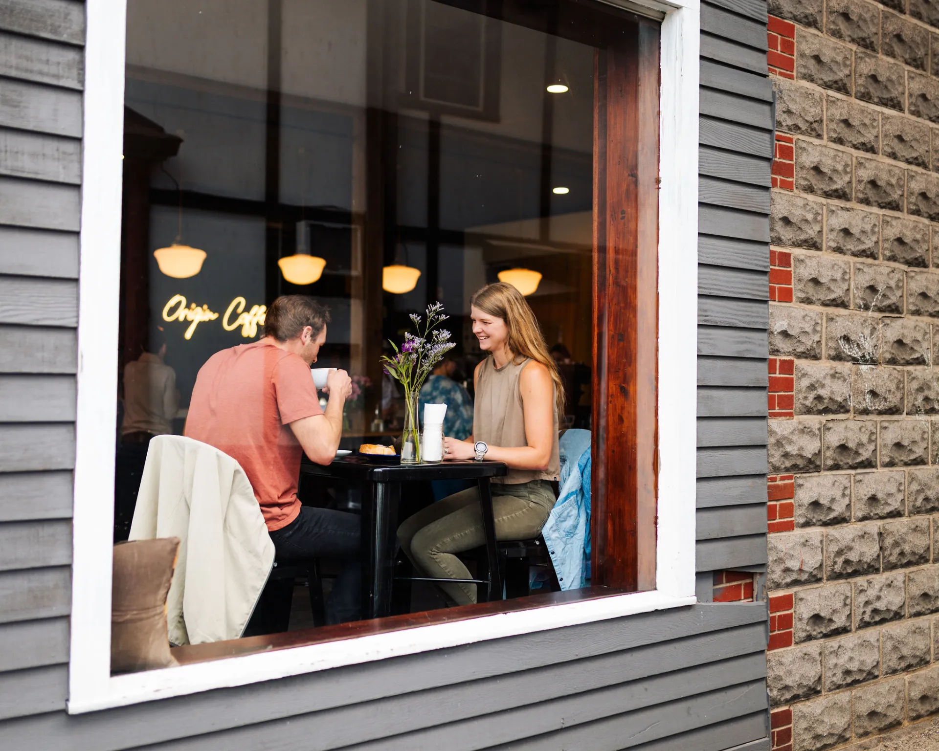 A couple sitting in the window at Origin Coffee Lake Placid.