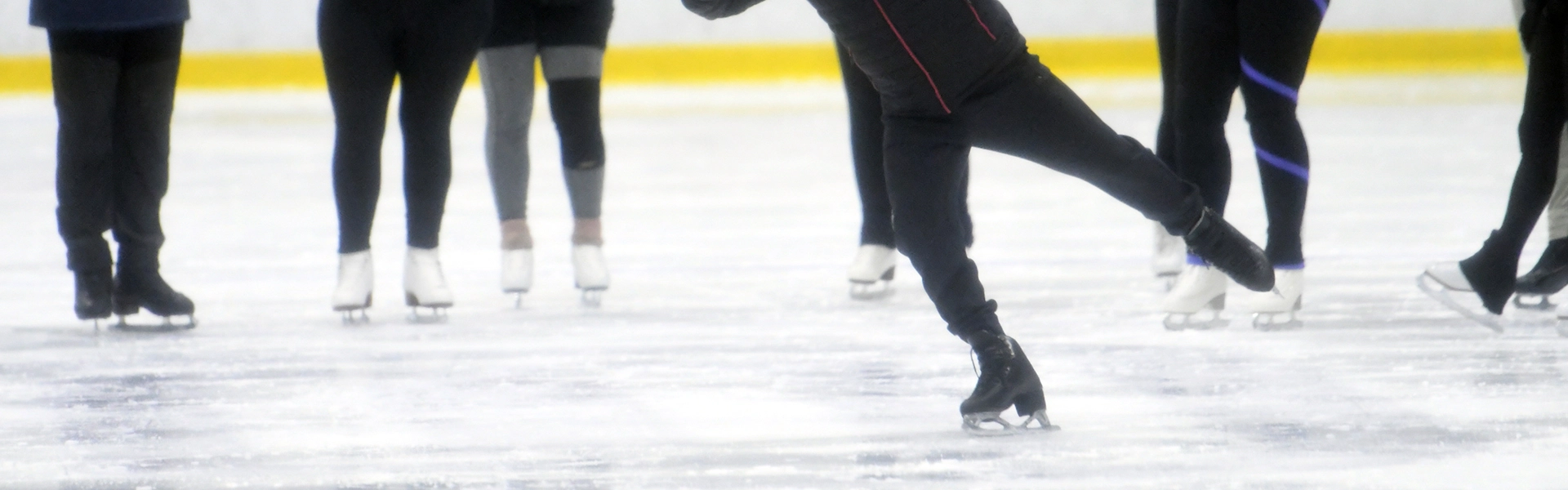 People wearing ice skates slide on the rink.  