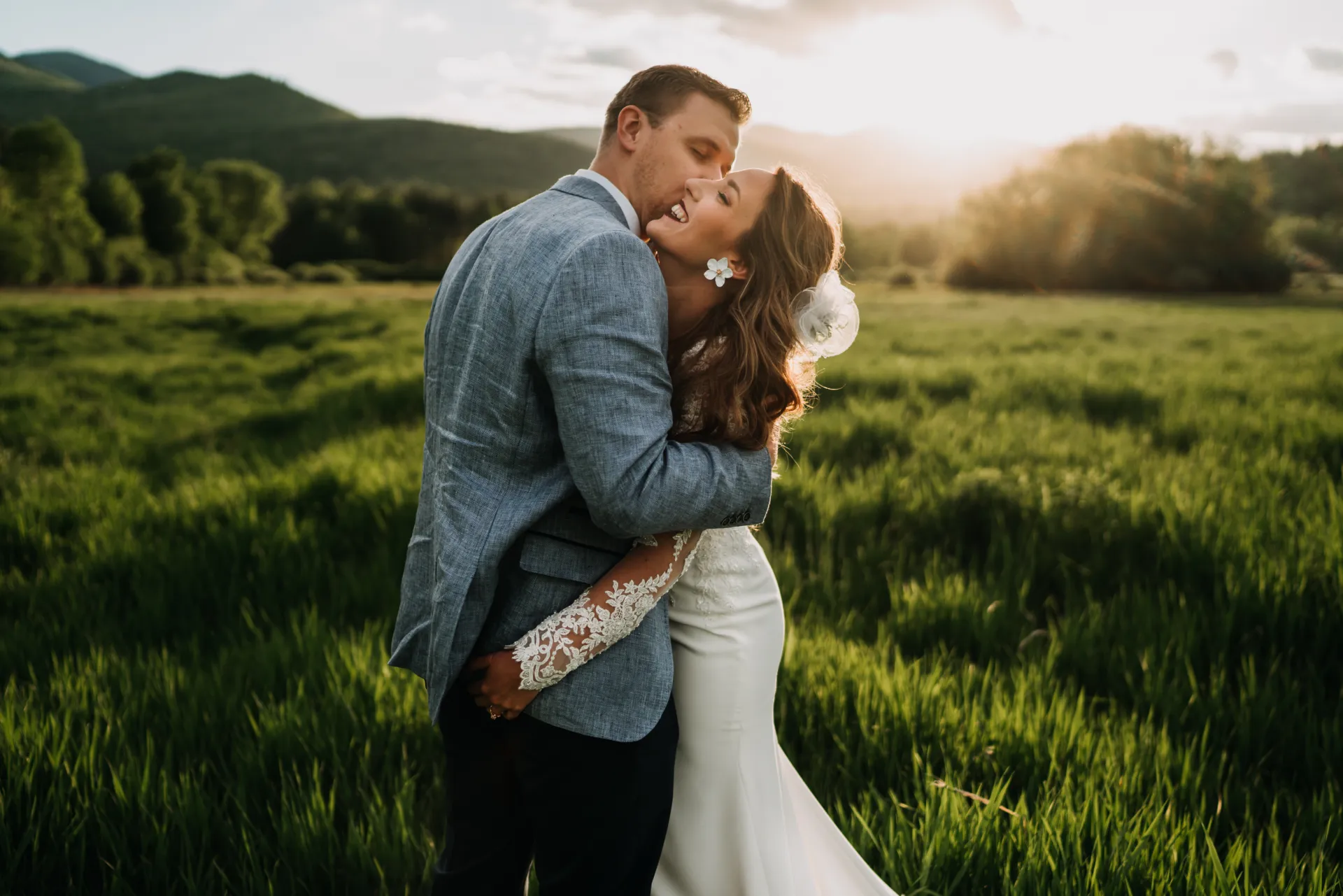married couple together in open field with mountains in the background