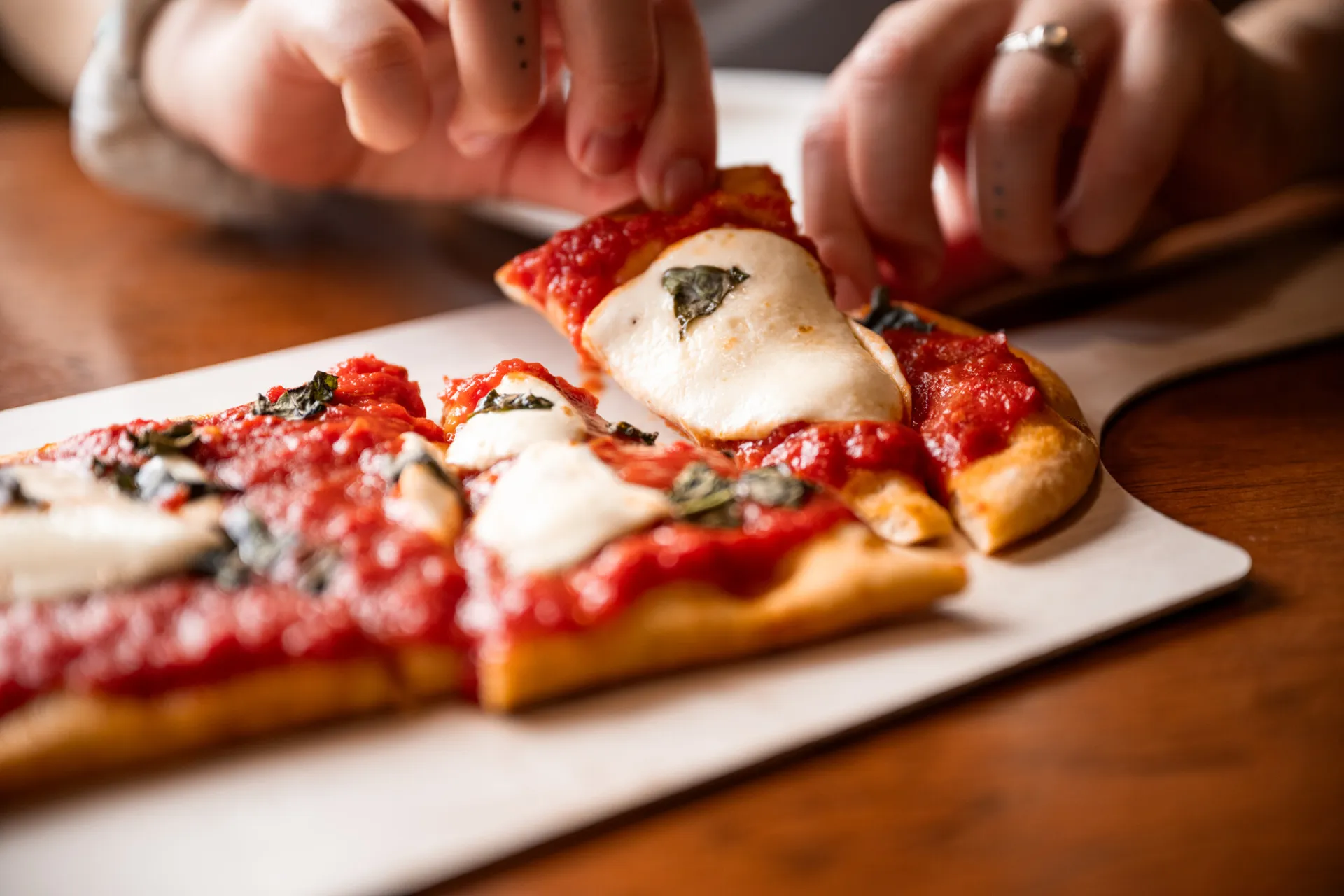 Pizza being pulled from a tray.