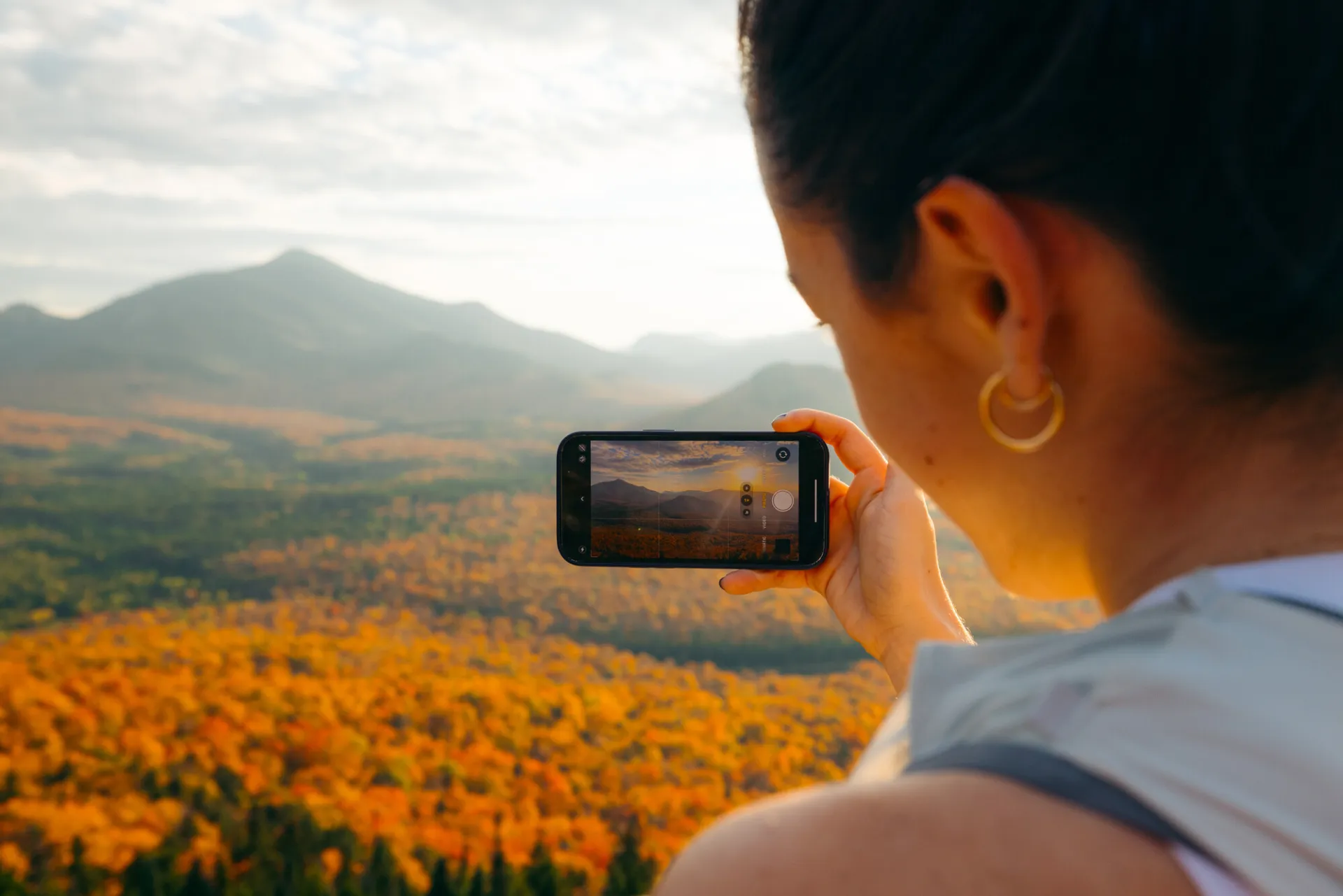 A woman takes a picture of a fall mountain range. 