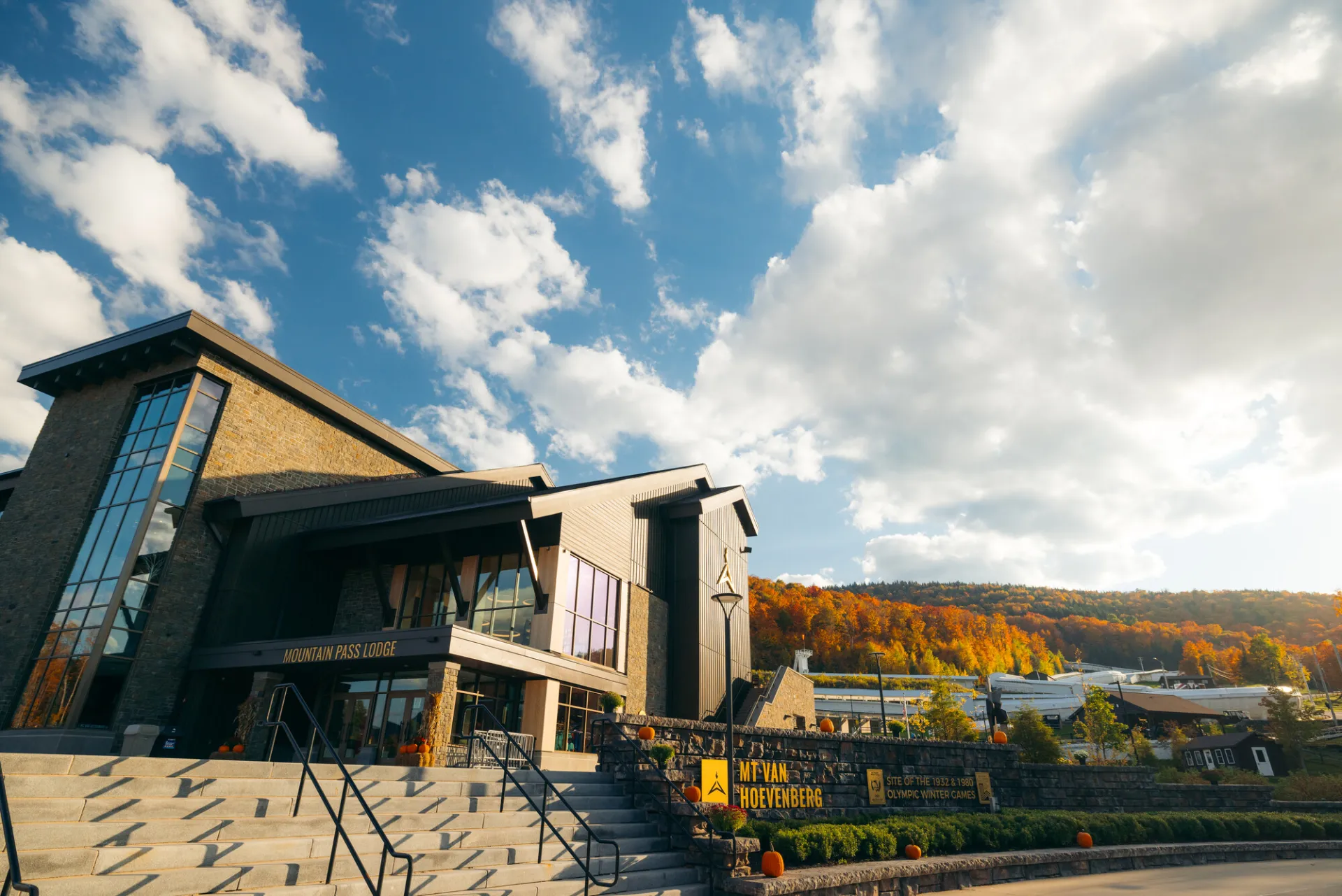 A state of the art lodge stands next to a bobsled track in fall.