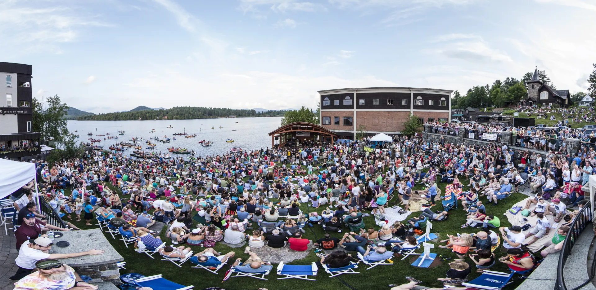 A large group of people gathered at a bandshell by the water