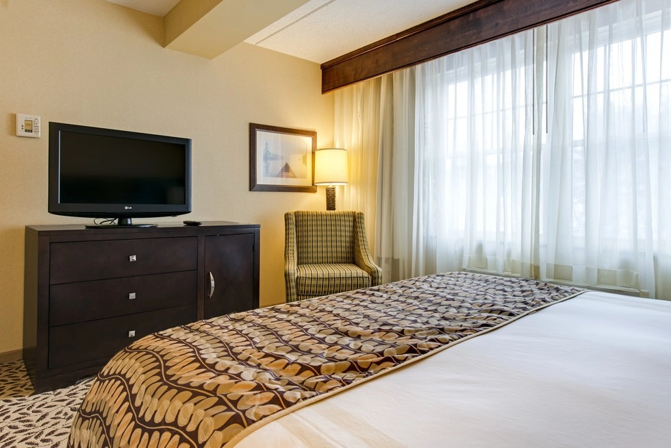 Bright room with bed, chair, desk and large windows.