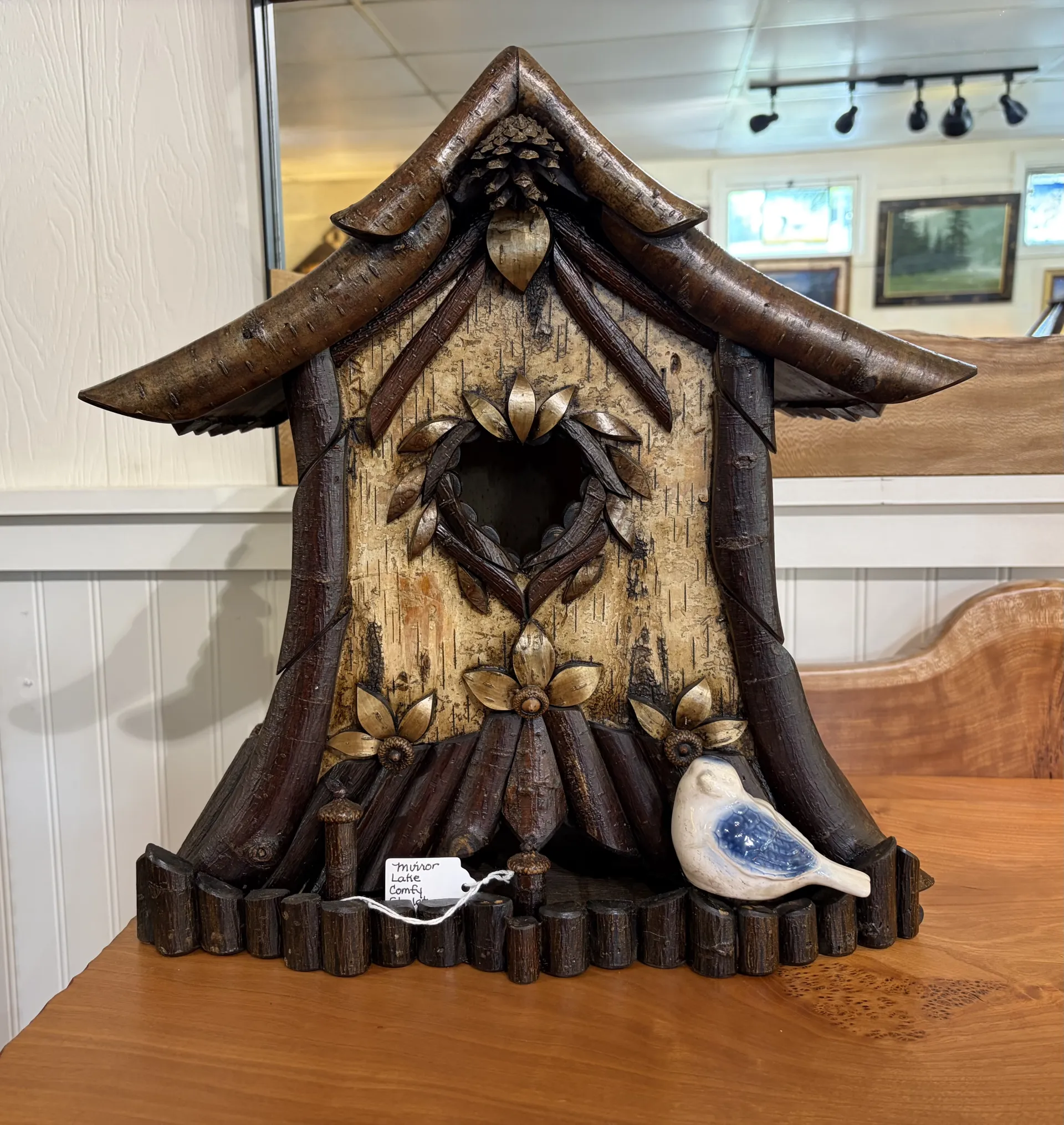 A rustic birdhouse made from twigs, birch bark, pine cones and various natural materials.