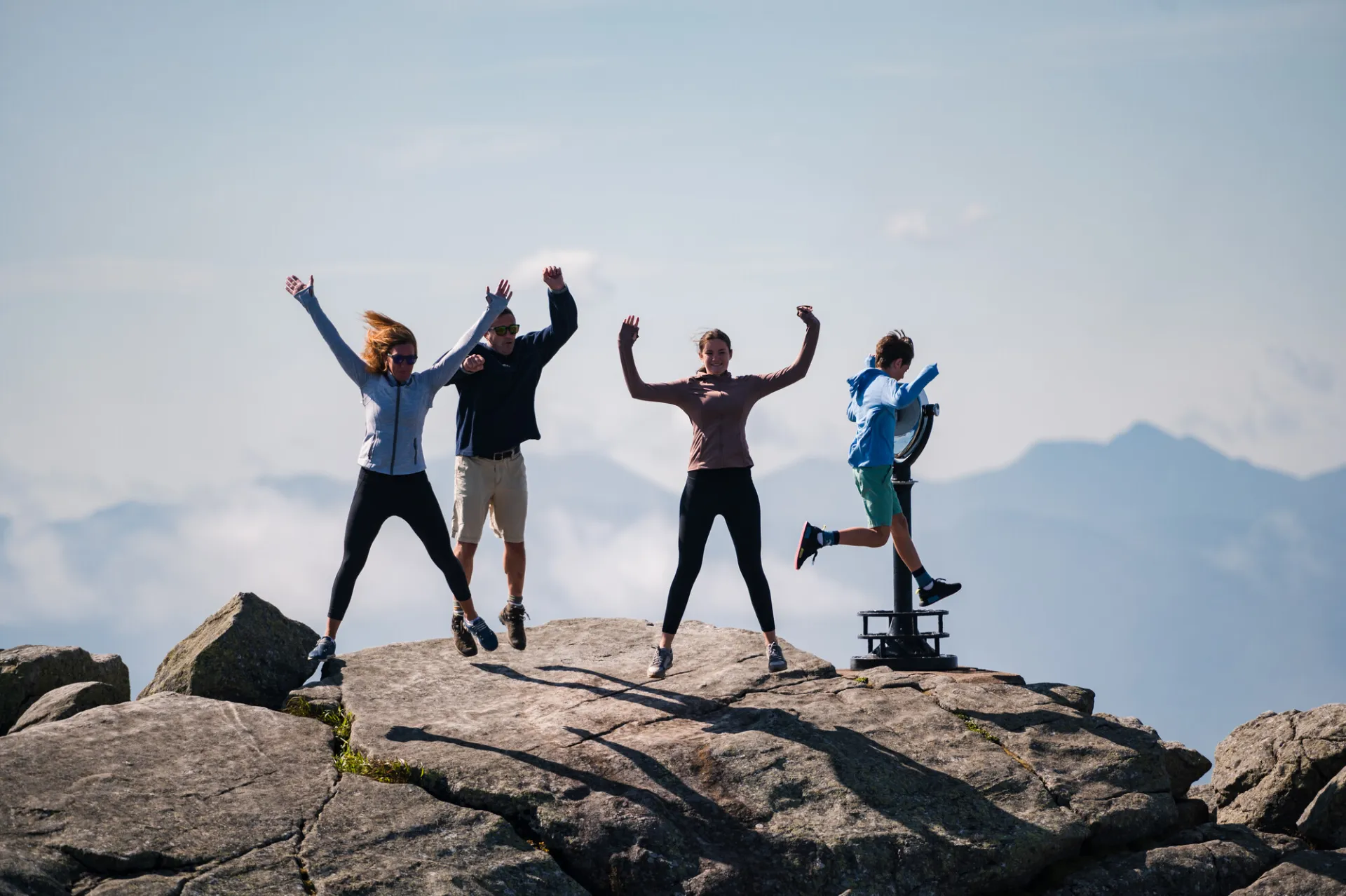 A family jumps for joy on top of a rocky mountain