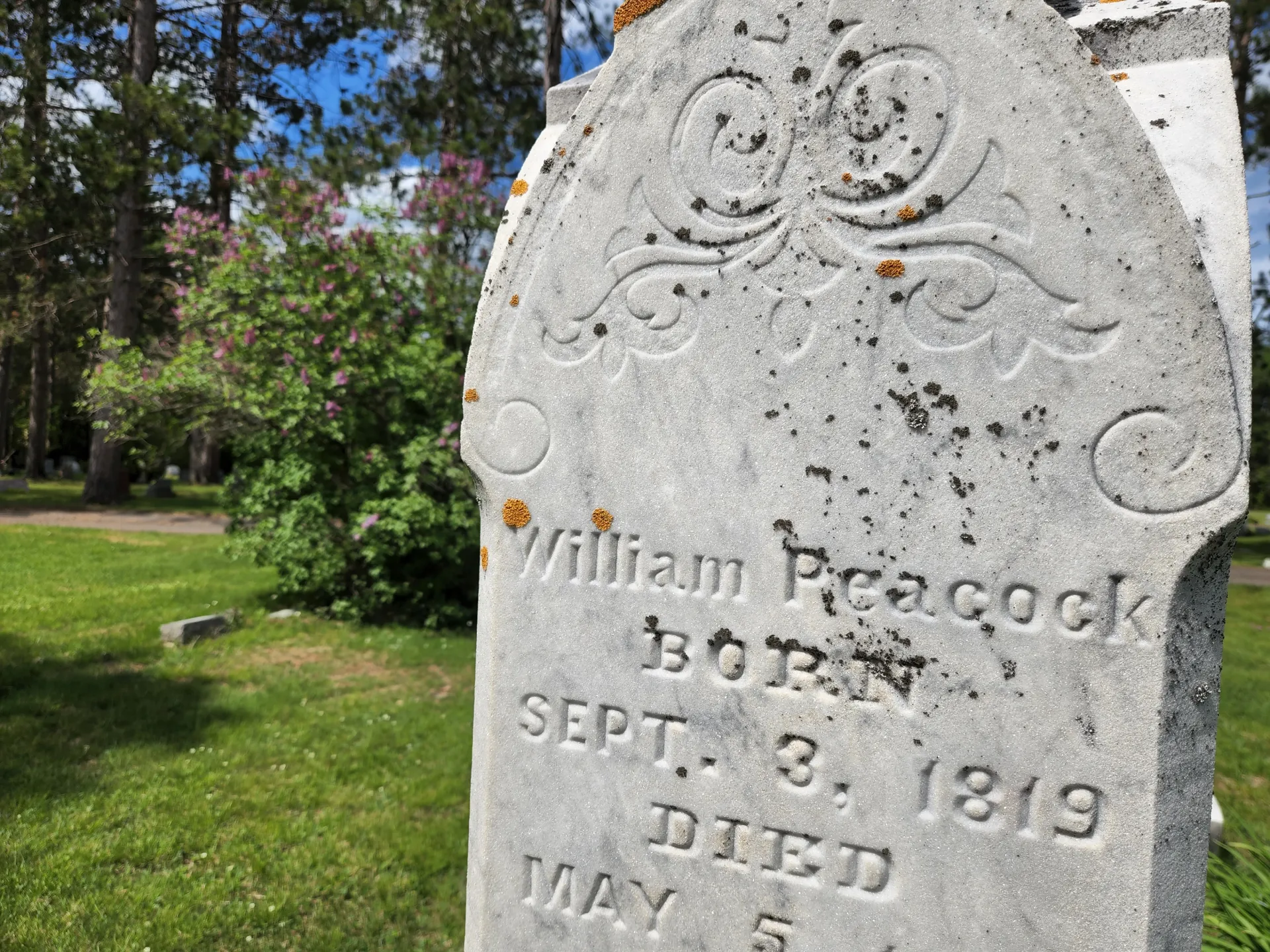 Close-up image of an old headstone with the name William Peacock and the birth date of September 3, 1819